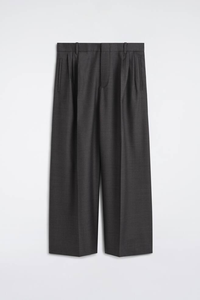 Plissierte Wide-Leg-Hose mit lockerer Passform in Dunkelgrau, von vorne gezeigt, die ihre strukturierte Silhouette und die entlang jedes Hosenbeins verlaufenden BÃ¼gelfalten hervorhebt. Die Hose verfÃ¼gt Ã¼ber doppelte Bundfalten vorn, einen Bund mit GÃ¼rtelschlaufen und senkrechte Paspeltaschen an den Seiten. - 1
