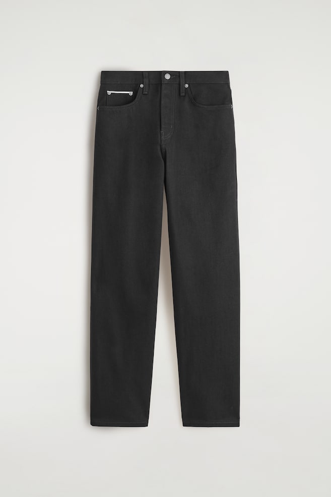 A pair of black, relaxed-fit, straight-leg jeans is presented from the FRONT. It is featuring a mid-rise waist, a shank button closure, and a five-pocket design with a small silver bar accenting the coin pocket. - 1