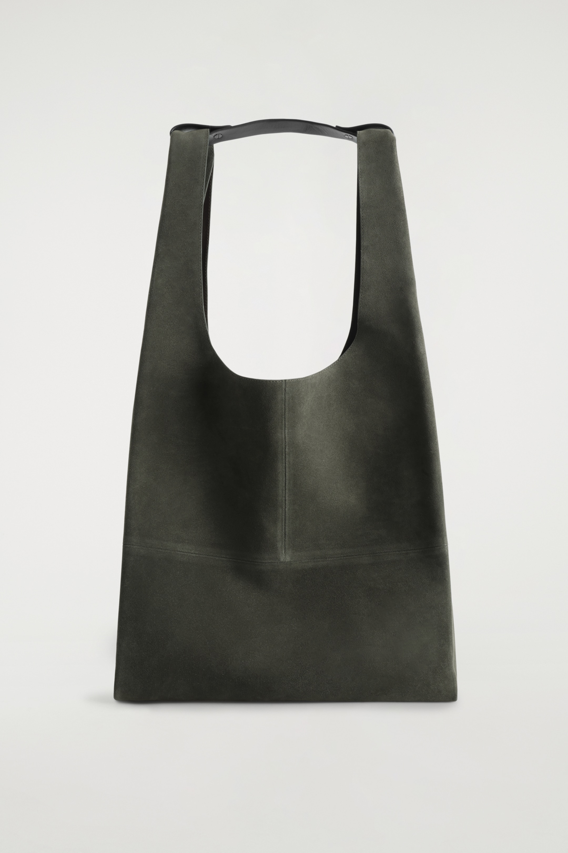 Ingrandisci l'immagine: Una borsa tote in camoscio verde oliva scuro presenta la sua parte anteriore, caratterizzata da un'ampia apertura a forma di U nella parte superiore, una cucitura verticale al centro e una cucitura orizzontale lungo la parte inferiore anteriore. Due tracolle in pelle nera emergono dalla parte superiore, fissate da una linguetta in pelle orizzontale.