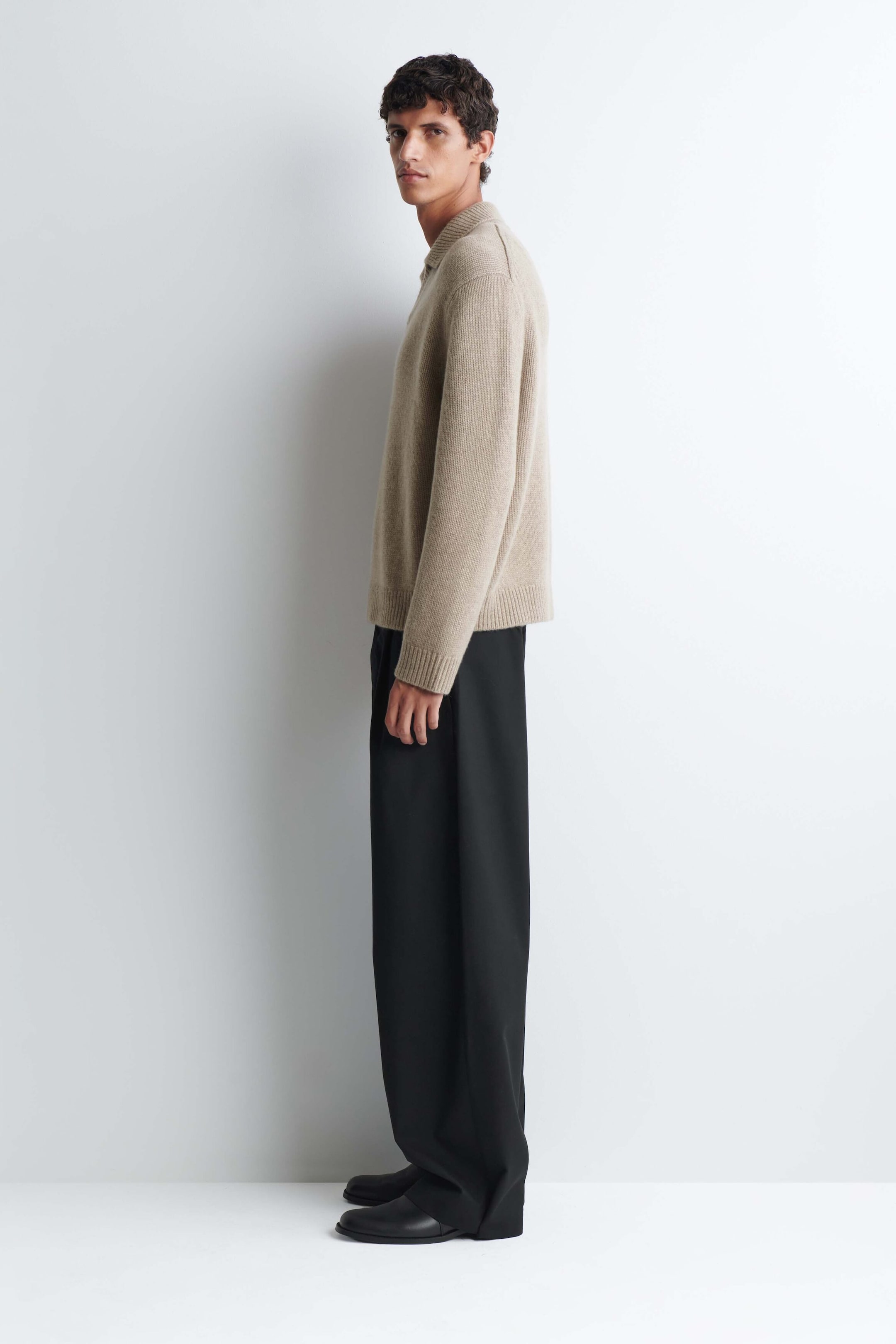 A chunky cashmere polo sweater in a light beige knit is worn by the model, who is standing in profile. The sweater features a classic polo collar, ribbed cuffs, and a ribbed hem, and is styled with black wide-leg trousers. A chunky cashmere polo sweater in a light beige knit is worn by the model, who is standing in profile. The sweater features a classic polo collar, ribbed cuffs, and a ribbed hem, and is styled with black wide-leg trousers.