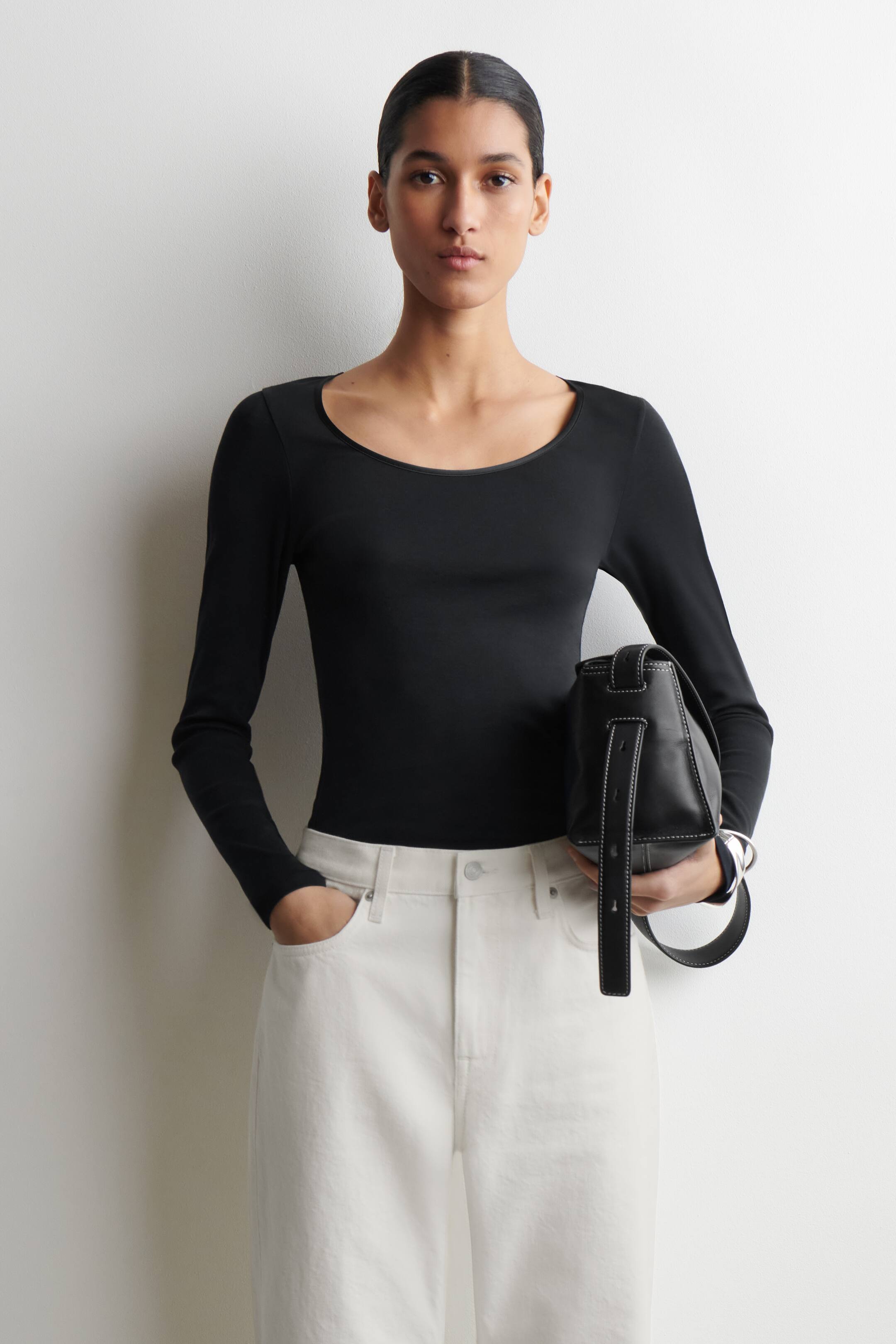 Agrandir l'image: Un haut noir à manches longues présente une silhouette lisse et ajustée avec un large décolleté rond, vu de face.