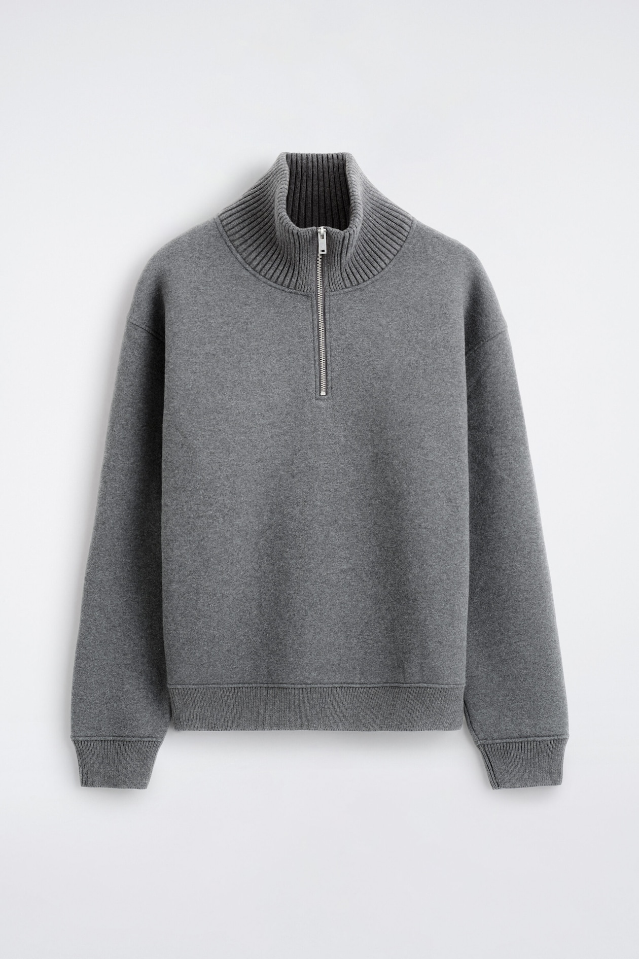 The cotton-wool jersey zip-up jumper is shown from the front, featuring a grey melange knit with a high ribbed collar and a silver-tone half-zip closure. It is designed with dropped shoulders, ribbed cuffs, and a matching ribbed hem.