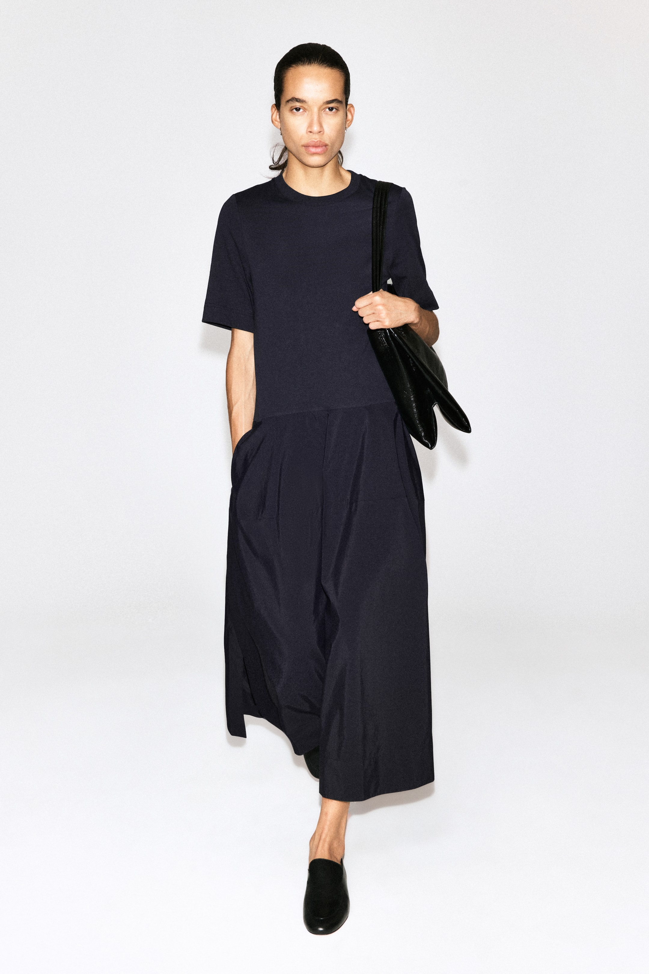 Größeres Bild ansehen: Der marineblaue Jumpsuit verfügt über eine lockere Passform, kurze Ärmel und einen Rundhalsausschnitt und geht in eine weit geschnittene, verkürzte Hose mit Bundfalten vorne über.