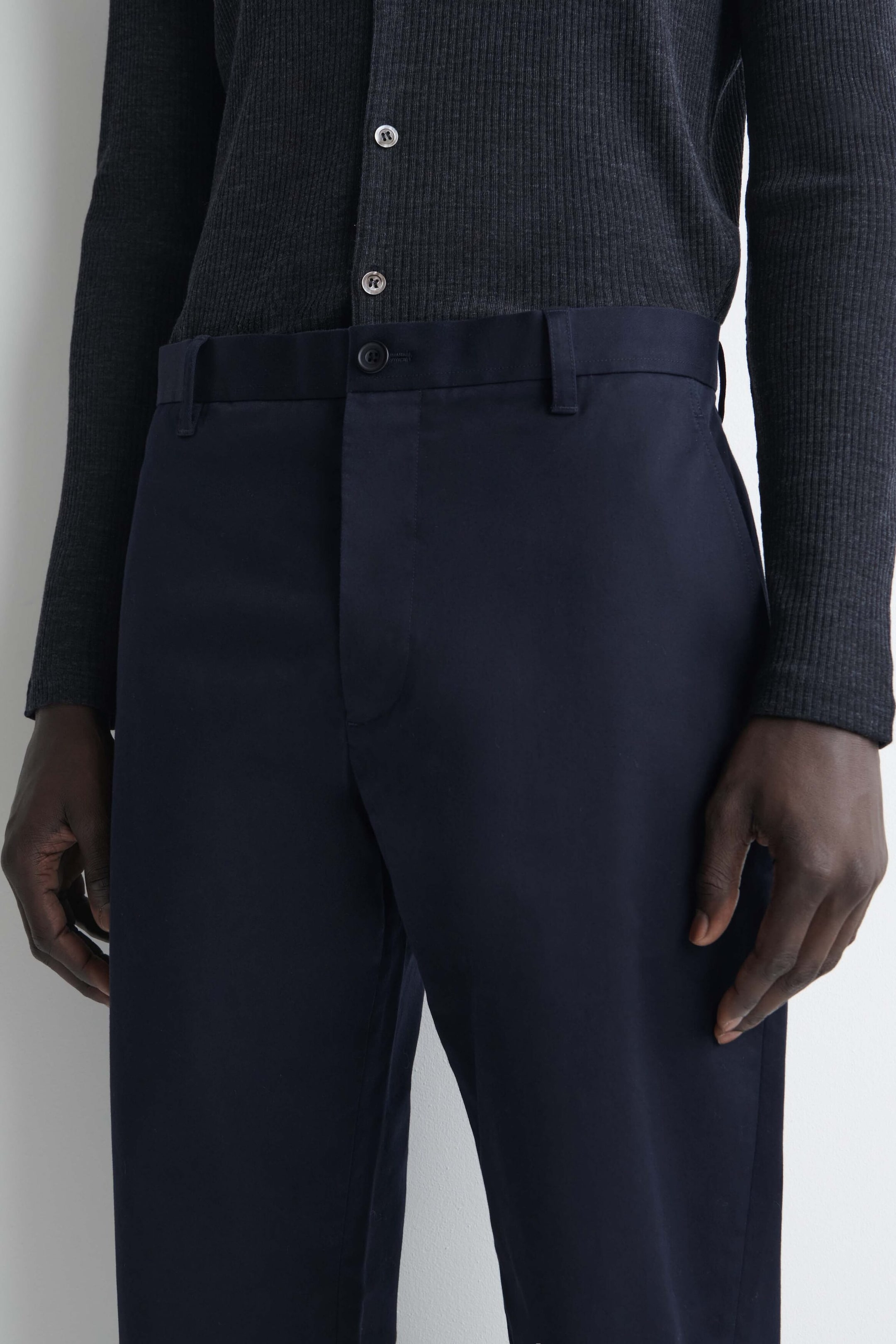 I chino slim fit a gamba dritta in cotone color blu navy sono mostrati dall’alto, con vita strutturata con passanti per cintura, chiusura con bottone tono su tono e apertura frontale nascosta. Un cardigan a coste grigio scuro è indossato infilato nella vita, mettendo in risalto il design pulito sul davanti e la vestibilità sartoriale dei pantaloni. I chino slim fit a gamba dritta in cotone color blu navy sono mostrati dall’alto, con vita strutturata con passanti per cintura, chiusura con bottone tono su tono e apertura frontale nascosta. Un cardigan a coste grigio scuro è indossato infilato nella vita, mettendo in risalto il design pulito sul davanti e la vestibilità sartoriale dei pantaloni.