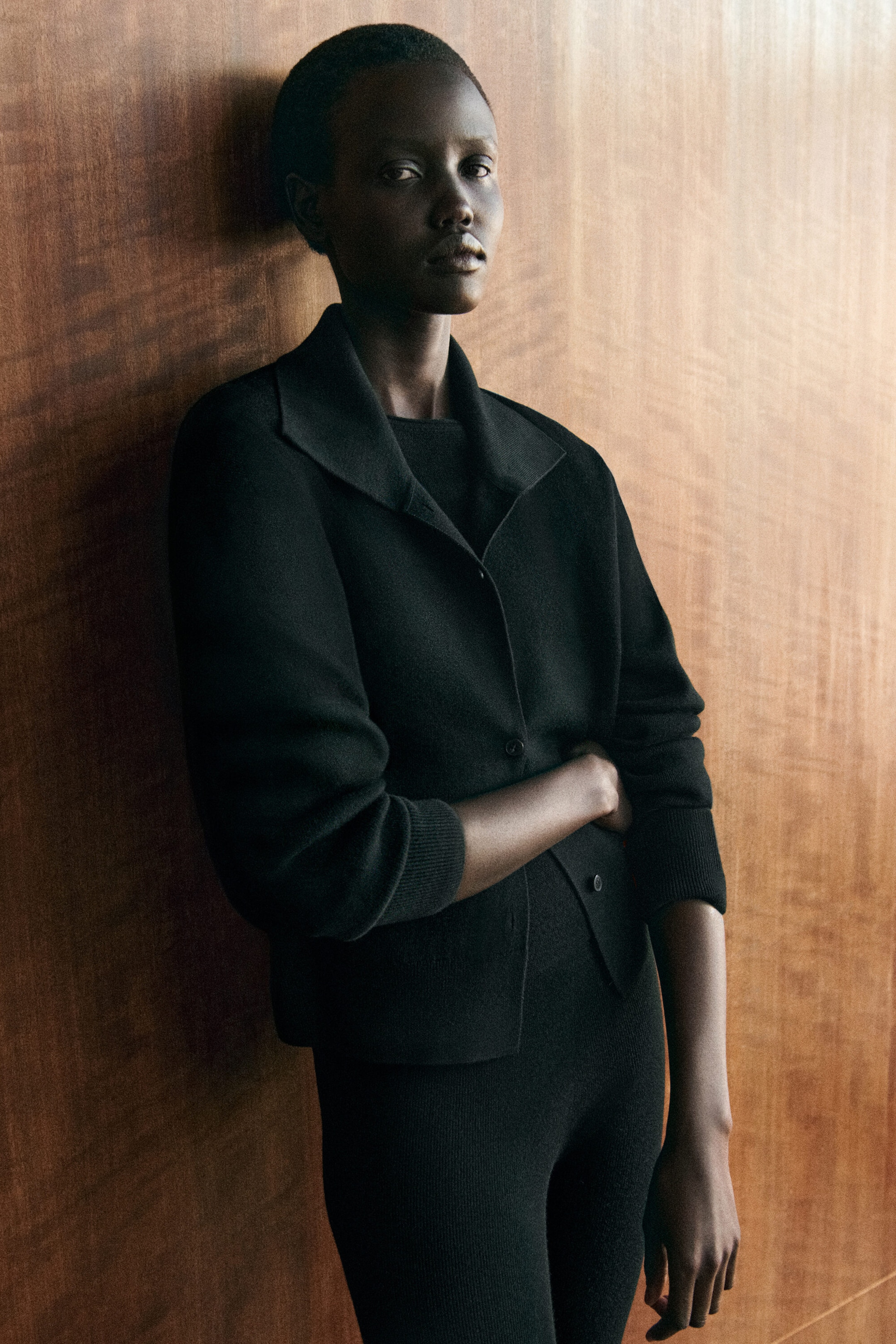 Le cardigan à col cheminée en laine mérinos est présenté en vue de trois quarts de face, avec une conception structurée à boutons sur le devant et un large col cheminée ouvert. Le cardigan noir met en valeur des manches longues avec des poignets côtelés et est porté par-dessus un haut en tricot noir assorti. Le cardigan à col cheminée en laine mérinos est présenté en vue de trois quarts de face, avec une conception structurée à boutons sur le devant et un large col cheminée ouvert. Le cardigan noir met en valeur des manches longues avec des poignets côtelés et est porté par-dessus un haut en tricot noir assorti.