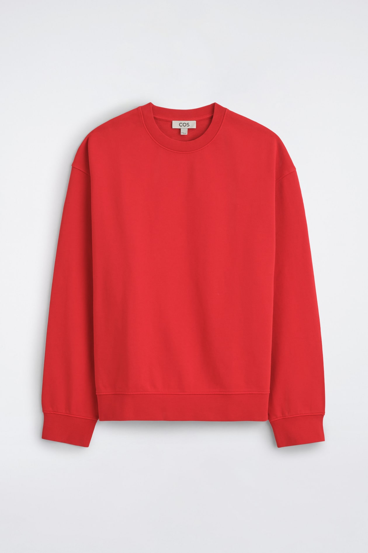 A bright red crew-neck sweatshirt is shown from the front, featuring long sleeves with dropped shoulders and ribbed trims at the collar, cuffs, and hem.