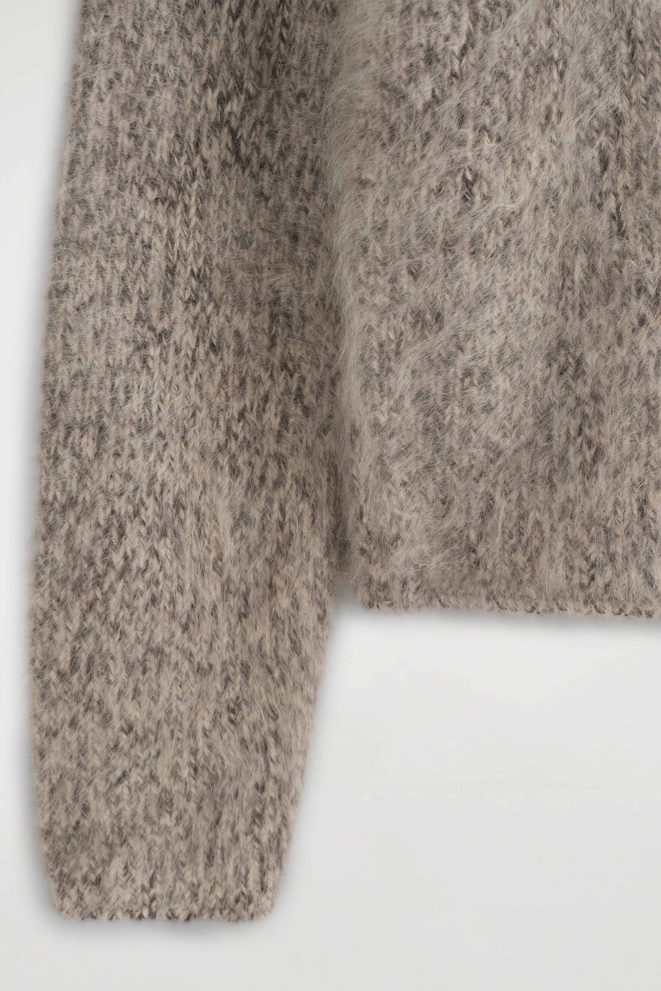Le chandail à col cheminée en cachemire brossé à mailles épaisses présente une texture douce et duveteuse ainsi qu’une construction en tricot chiné beige-gris, illustré en gros plan pour mettre en valeur le détail de la manche et de l’ourlet inférieur du corsage. Le chandail à col cheminée en cachemire brossé à mailles épaisses présente une texture douce et duveteuse ainsi qu’une construction en tricot chiné beige-gris, illustré en gros plan pour mettre en valeur le détail de la manche et de l’ourlet inférieur du corsage.