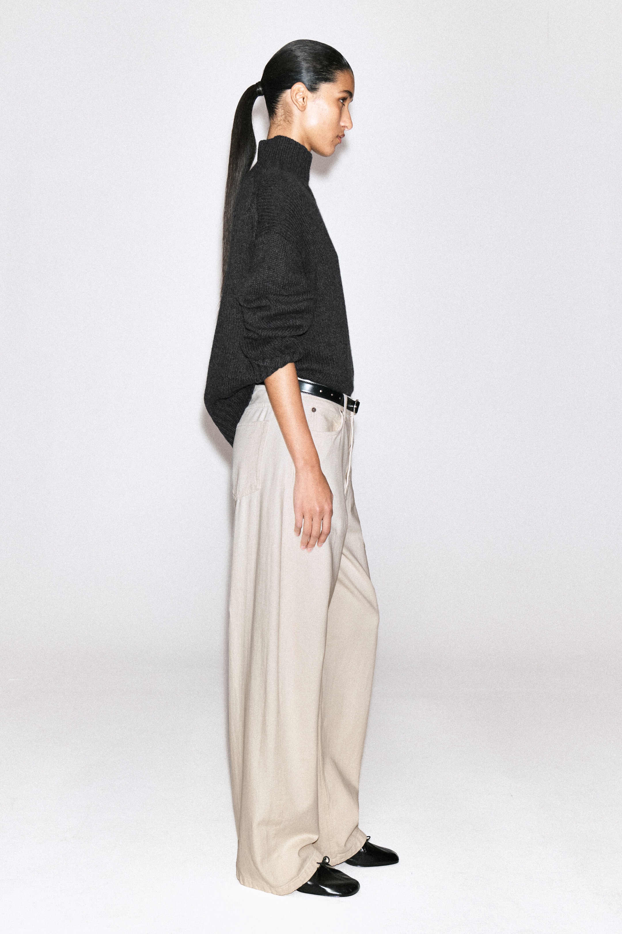 The Lagoon wide-leg jeans in a light beige wash are showcasing a relaxed, wide-leg silhouette in a side view facing right. The jeans feature a high-rise waist cinched with a black leather belt and are pooling slightly over black shoes at the hem. The Lagoon wide-leg jeans in a light beige wash are showcasing a relaxed, wide-leg silhouette in a side view facing right. The jeans feature a high-rise waist cinched with a black leather belt and are pooling slightly over black shoes at the hem.