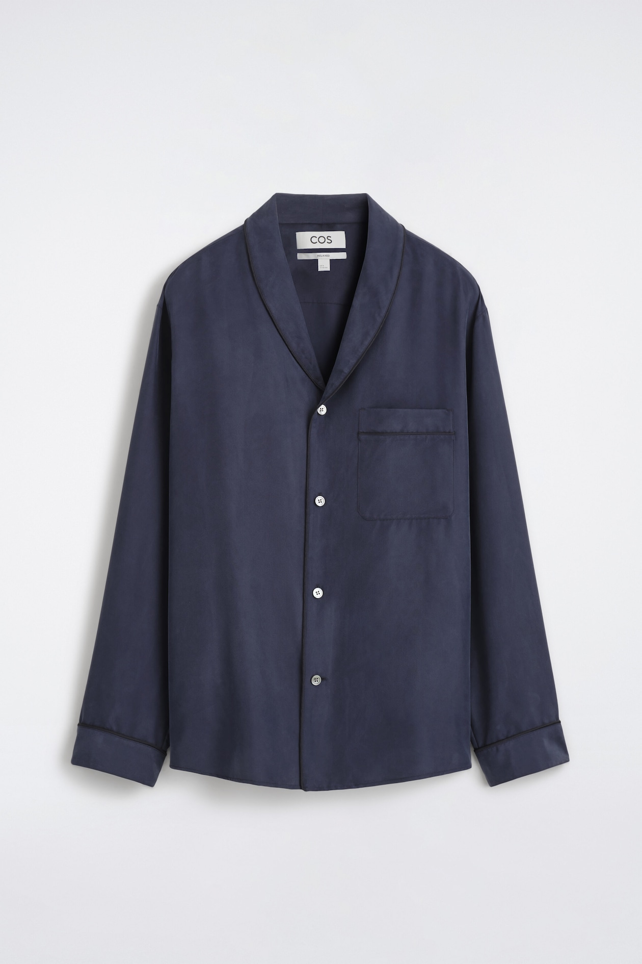 A navy blue long-sleeved shirt is shown front-facing, featuring a shawl collar with thin dark piping along the edge and a button-front closure with light-coloured buttons. The shirt includes a single chest patch pocket and cuffs, both finished with matching piped trim.