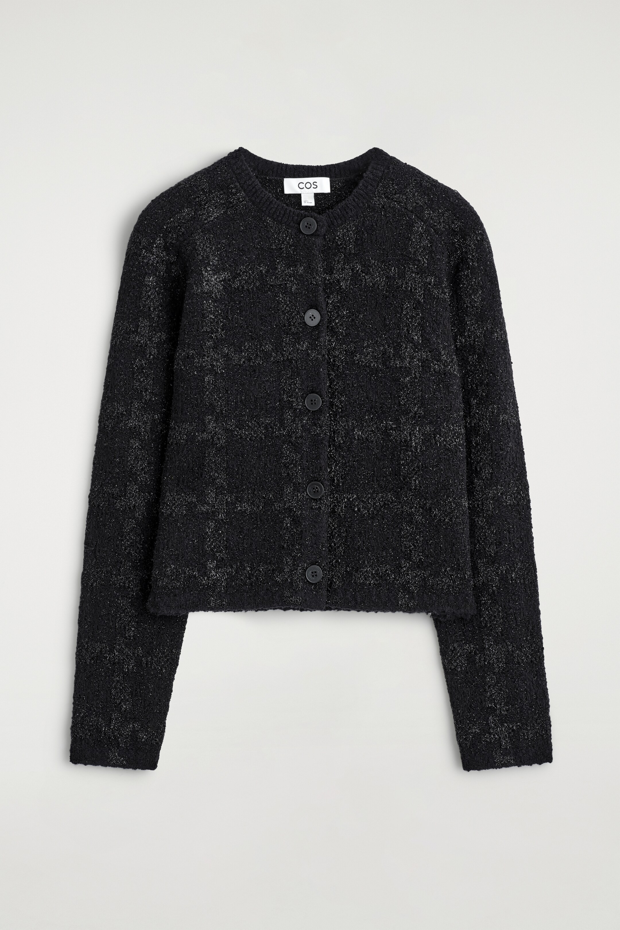 Agrandir l'image: Un cardigan en tricot bouclé noir est présenté de FACE, avec des fils métalliques scintillants formant un motif à carreaux discret. Il a un col rond, des manches longues et une fermeture à cinq boutons noirs sur le devant.