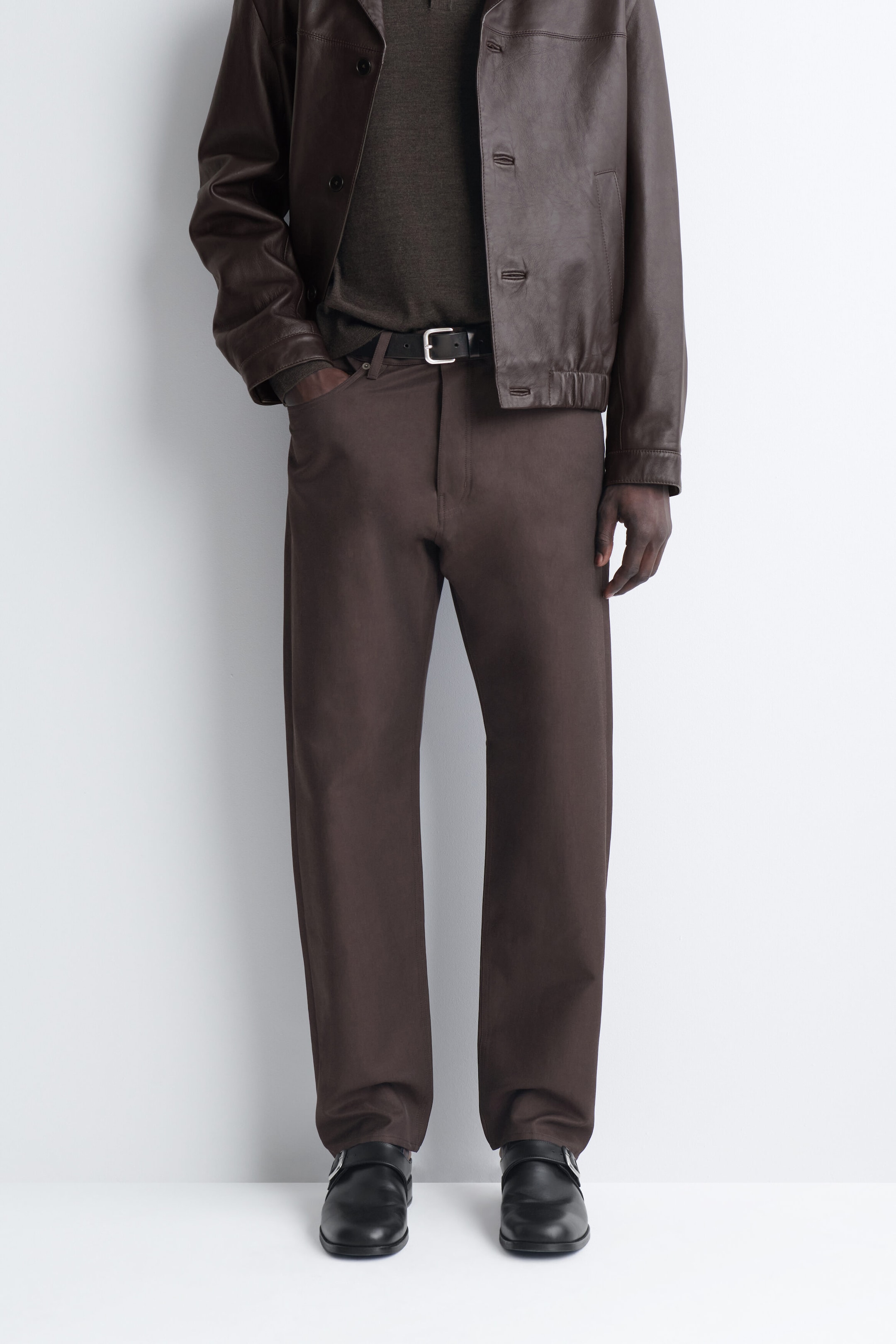 The signature regular-fit straight-leg jeans in dark brown are being worn in a front-facing view, showcasing their structured, straight-leg silhouette and mid-rise waist. They are styled with a black leather belt through the belt loops, with one hand resting in the front pocket to highlight the classic five-pocket design. The signature regular-fit straight-leg jeans in dark brown are being worn in a front-facing view, showcasing their structured, straight-leg silhouette and mid-rise waist. They are styled with a black leather belt through the belt loops, with one hand resting in the front pocket to highlight the classic five-pocket design.