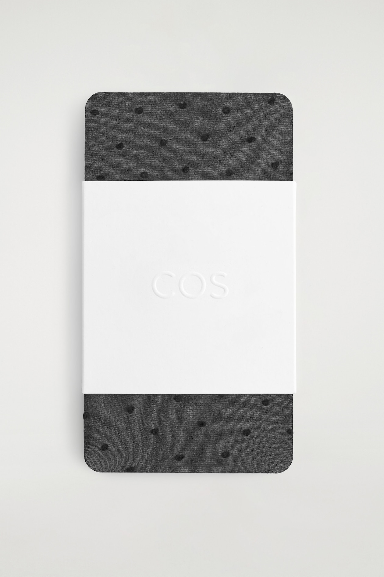 These sheer, dark grey socks featuring a black polka-dot jacquard pattern are shown folded flat, with a wide white paper band embossed with a logo wrapped around the centre.