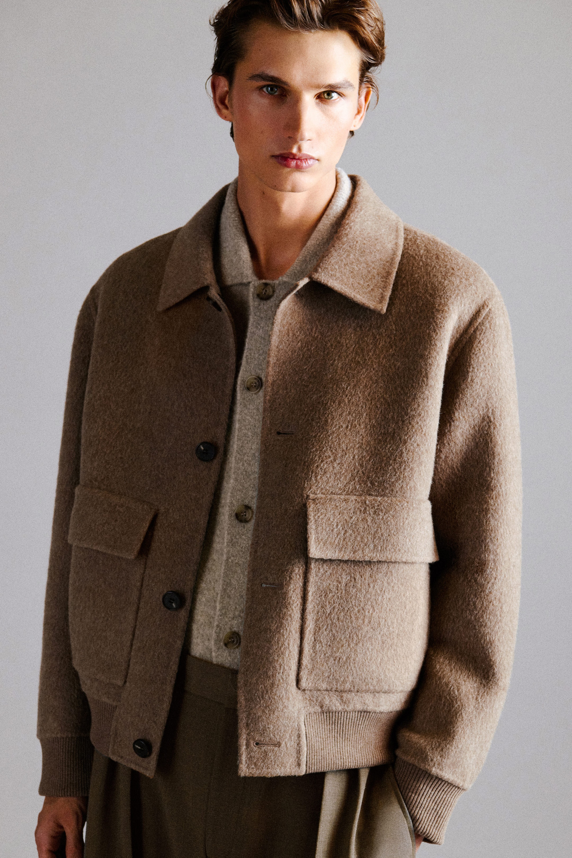 A textured taupe-brown wool-blend jacket is shown from the front, highlighting its relaxed fit, spread collar, and button-front closure. The jacket features large front flap pockets, along with ribbed cuffs and a ribbed hem, and is layered over a light beige knit polo. A textured taupe-brown wool-blend jacket is shown from the front, highlighting its relaxed fit, spread collar, and button-front closure. The jacket features large front flap pockets, along with ribbed cuffs and a ribbed hem, and is layered over a light beige knit polo.