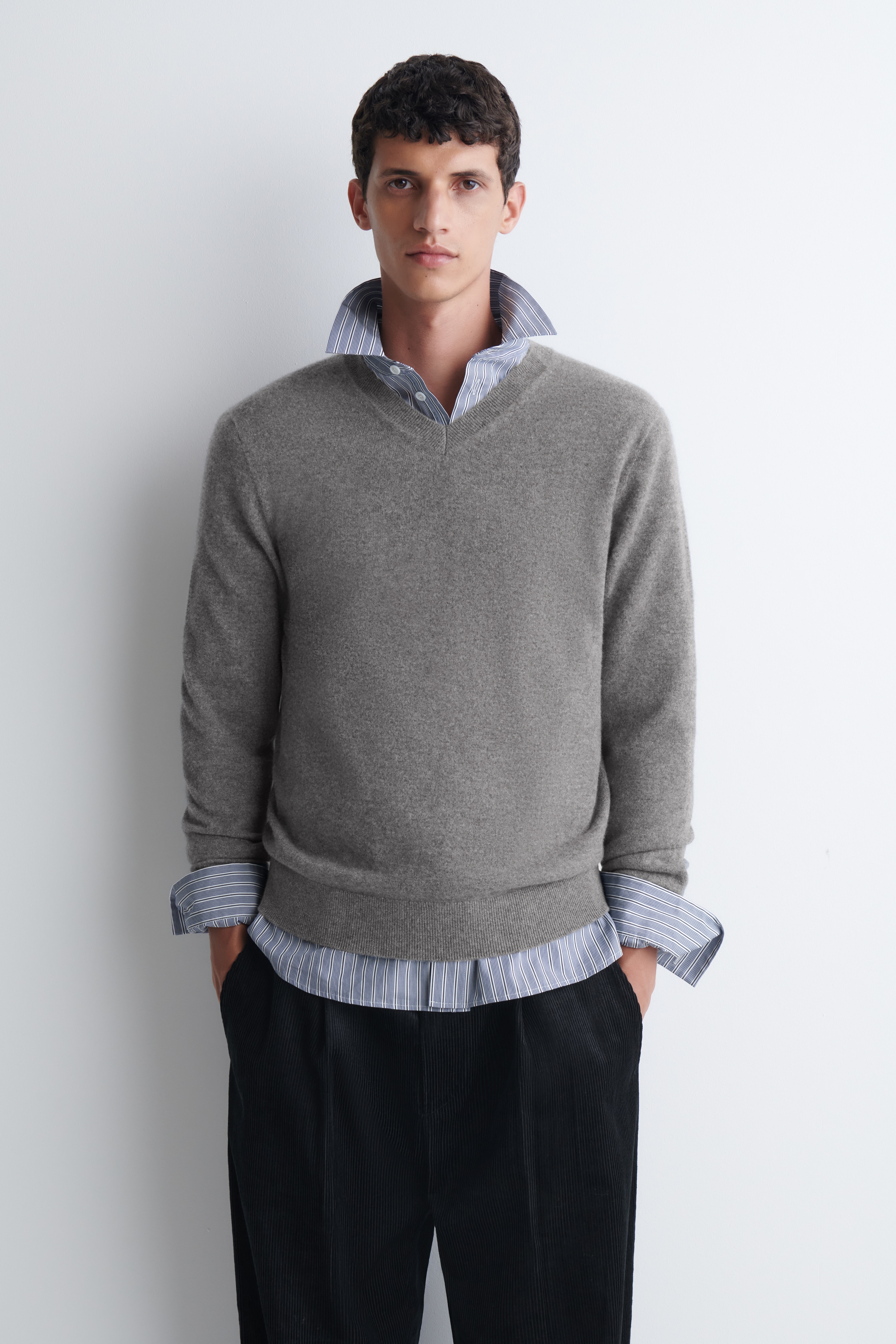 Il pullover in cashmere con scollo a V Ã¨ ripreso frontalmente, caratterizzato da una maglia mÃ©lange grigia testurizzata con scollo a V a coste, maniche lunghe con polsini a coste e fondo a coste abbinato.