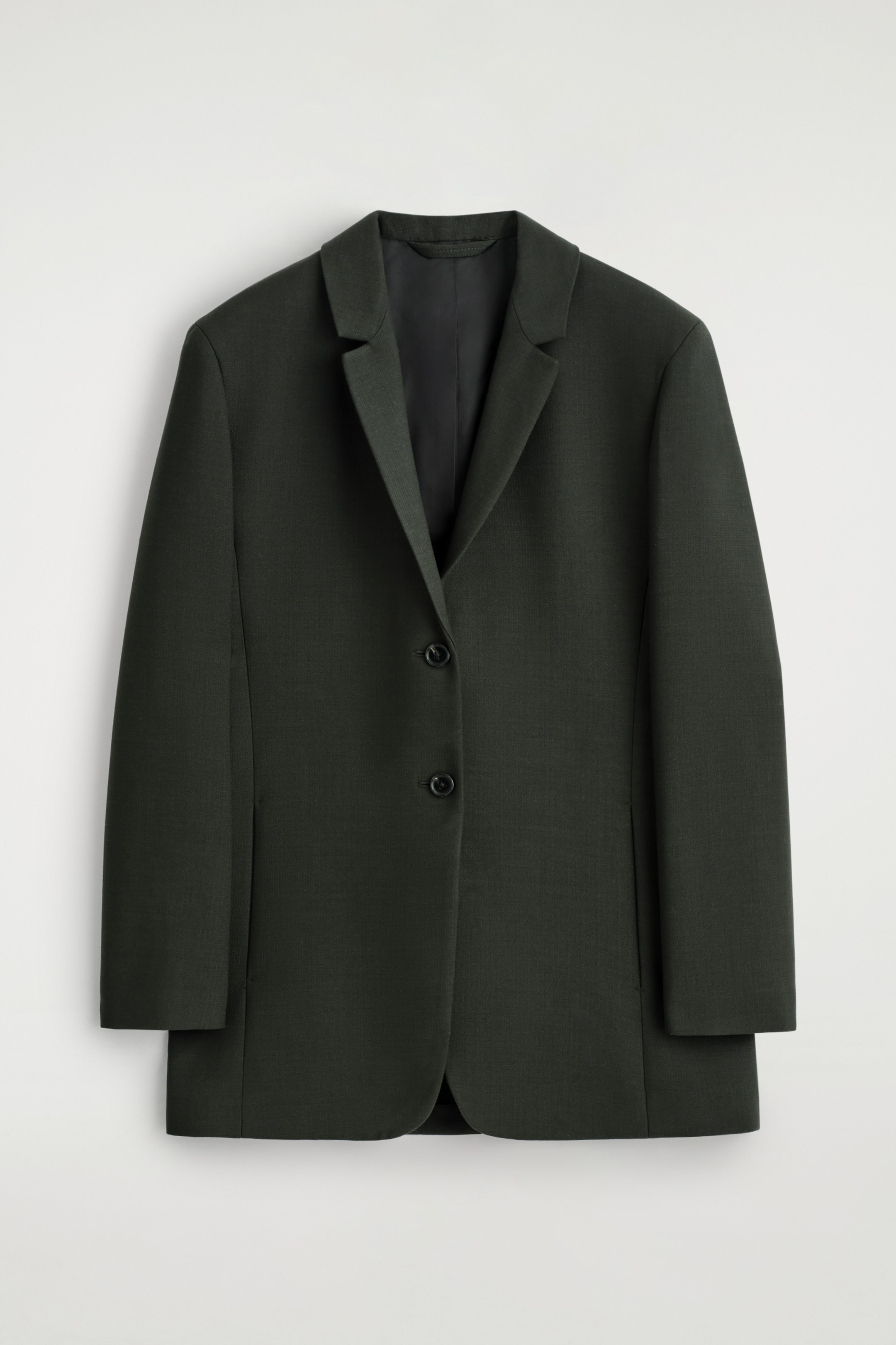 Grösseres Bild ansehen: Ein tiefgrünes Blazer wird von VORNE gezeigt, mit einem stromlinienförmigen, langen Schnitt, Einkerbung am Revers und einer einreihigen Knopfleiste, die durch zwei schwarze Knöpfe geschlossen wird.