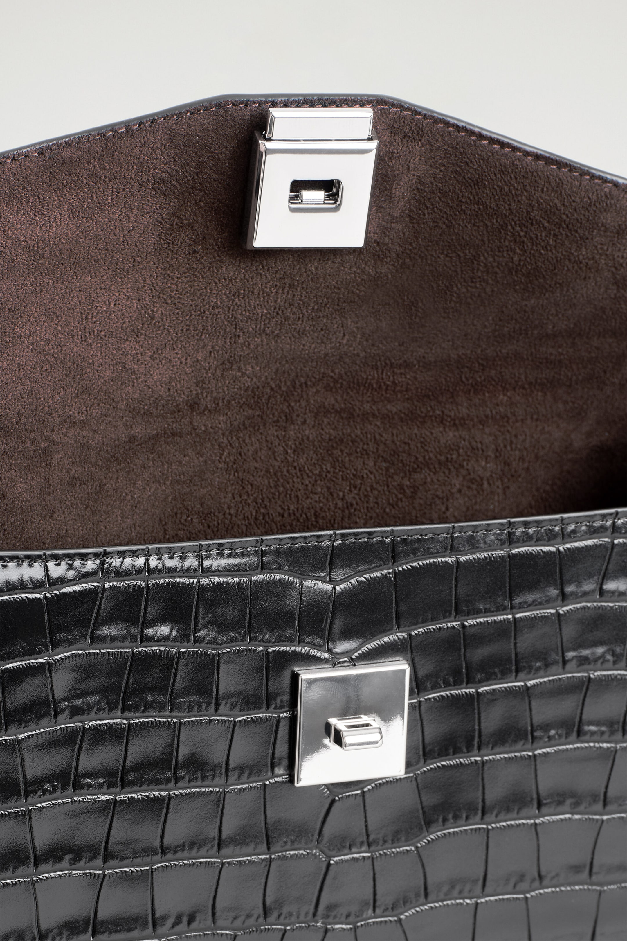 The Envelope Clasp Pouch in black croc-effect leather is shown from an open front view, revealing a dark brown suede-like interior lining. The pouch features a glossy, croc-embossed exterior texture and a silver-tone metal turn-lock clasp. The Envelope Clasp Pouch in black croc-effect leather is shown from an open front view, revealing a dark brown suede-like interior lining. The pouch features a glossy, croc-embossed exterior texture and a silver-tone metal turn-lock clasp.