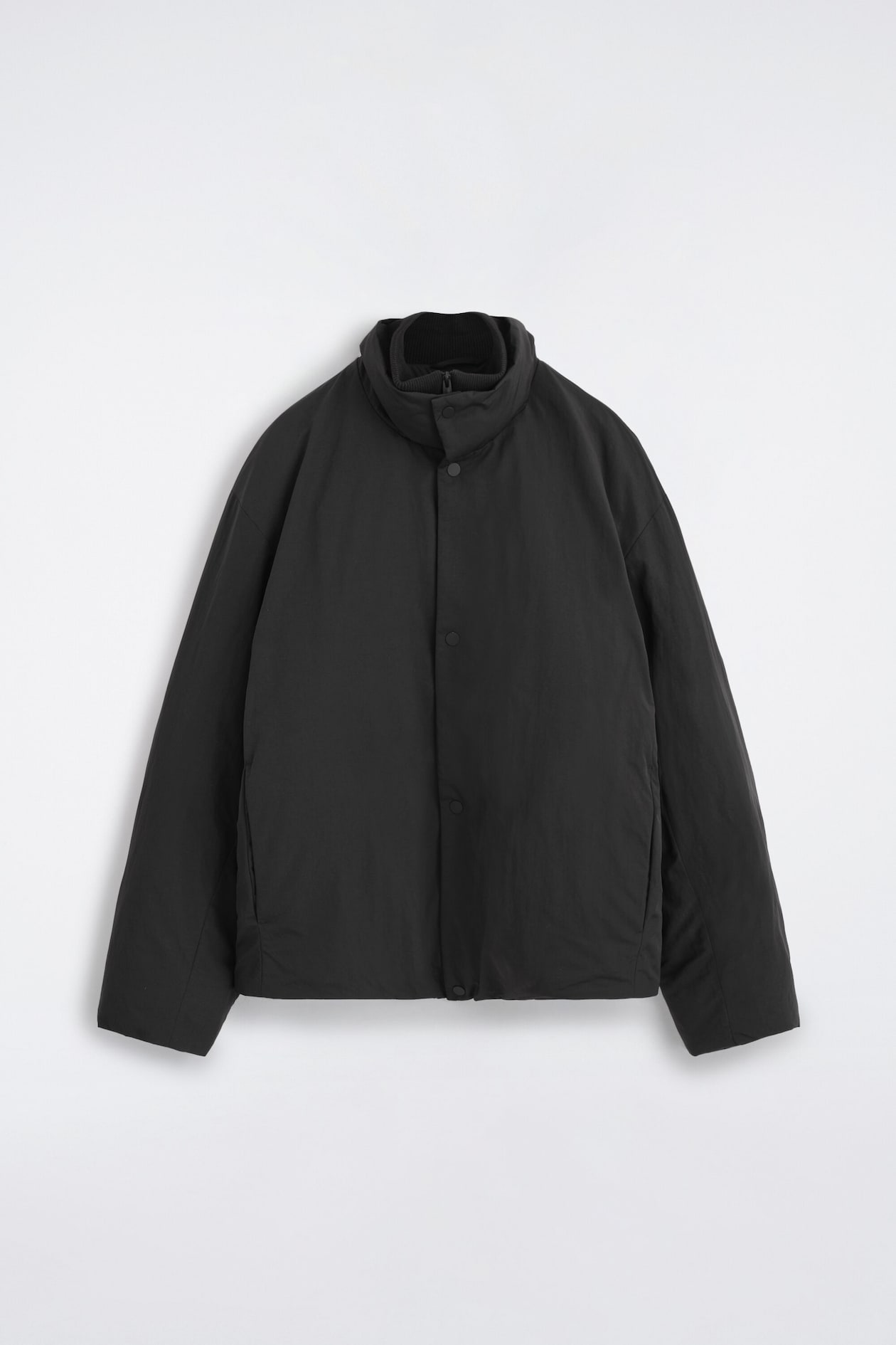 This black padded funnel-neck down jacket is facing forward, showcasing a high double collar with a ribbed inner layer and snap-button placket. The jacket presents a minimalist silhouette with long sleeves and subtle side welt pockets.