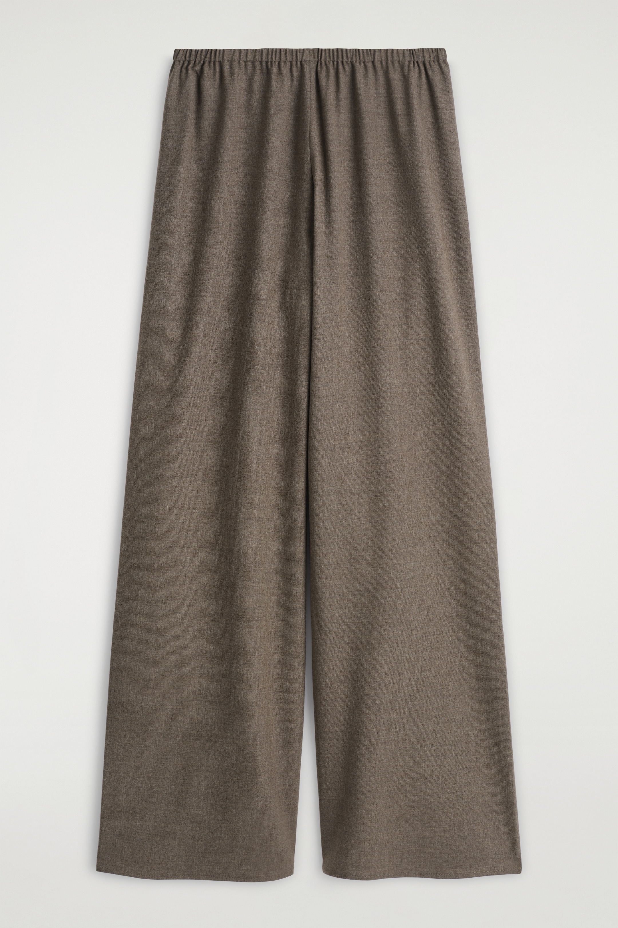 Grösseres Bild ansehen: Ein Paar braune, weit geschnittene Hosen wird flach präsentiert, mit der Vorderseite nach vorne. Die Hosen verfügen über einen elastischen, gerafften Bund und eine subtile gewebte Textur, wobei die Beine in einem entspannten, geraden Schnitt fallen.