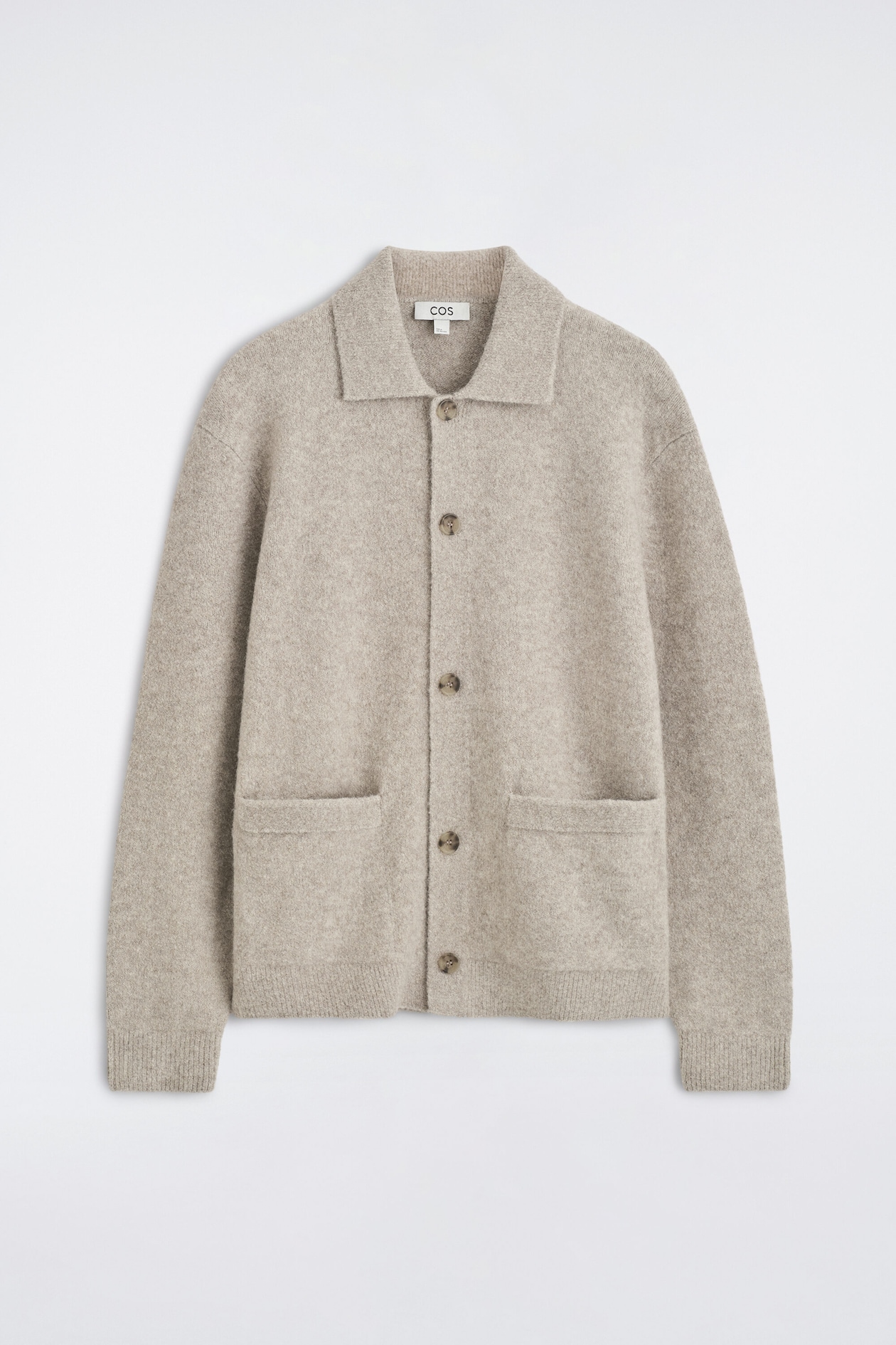 A light beige mélange knit cardigan is displayed front-facing, featuring a classic collar, a five-button closure, and two front patch pockets. The long-sleeved garment shows ribbed cuffs and a ribbed hem with a soft, brushed texture.