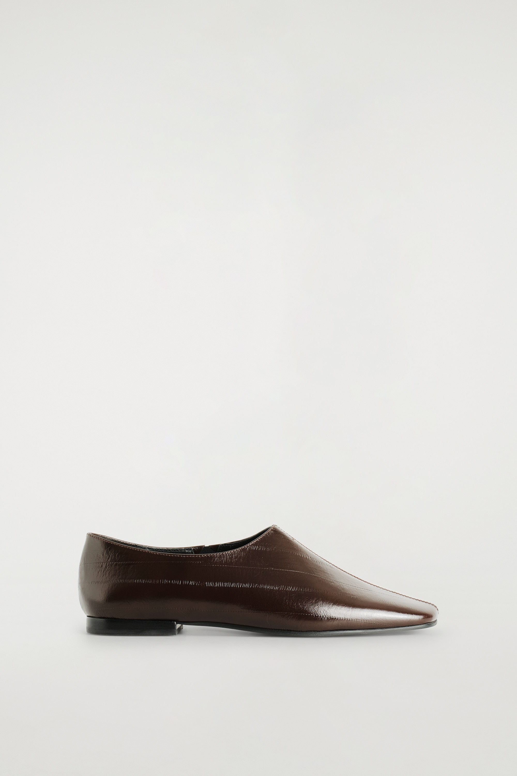 Une paire de chaussures plates en cuir brun foncÃ©, Ã  finition brillante, est prÃ©sentÃ©e vue de dessus, avec un bout carrÃ© et une finition texturÃ©e effet anguille. Les chaussures prÃ©sentent une couture centrale apparente et de discrÃ¨tes surpiqÃ»res qui rayonnent en diagonale sur lâavant.