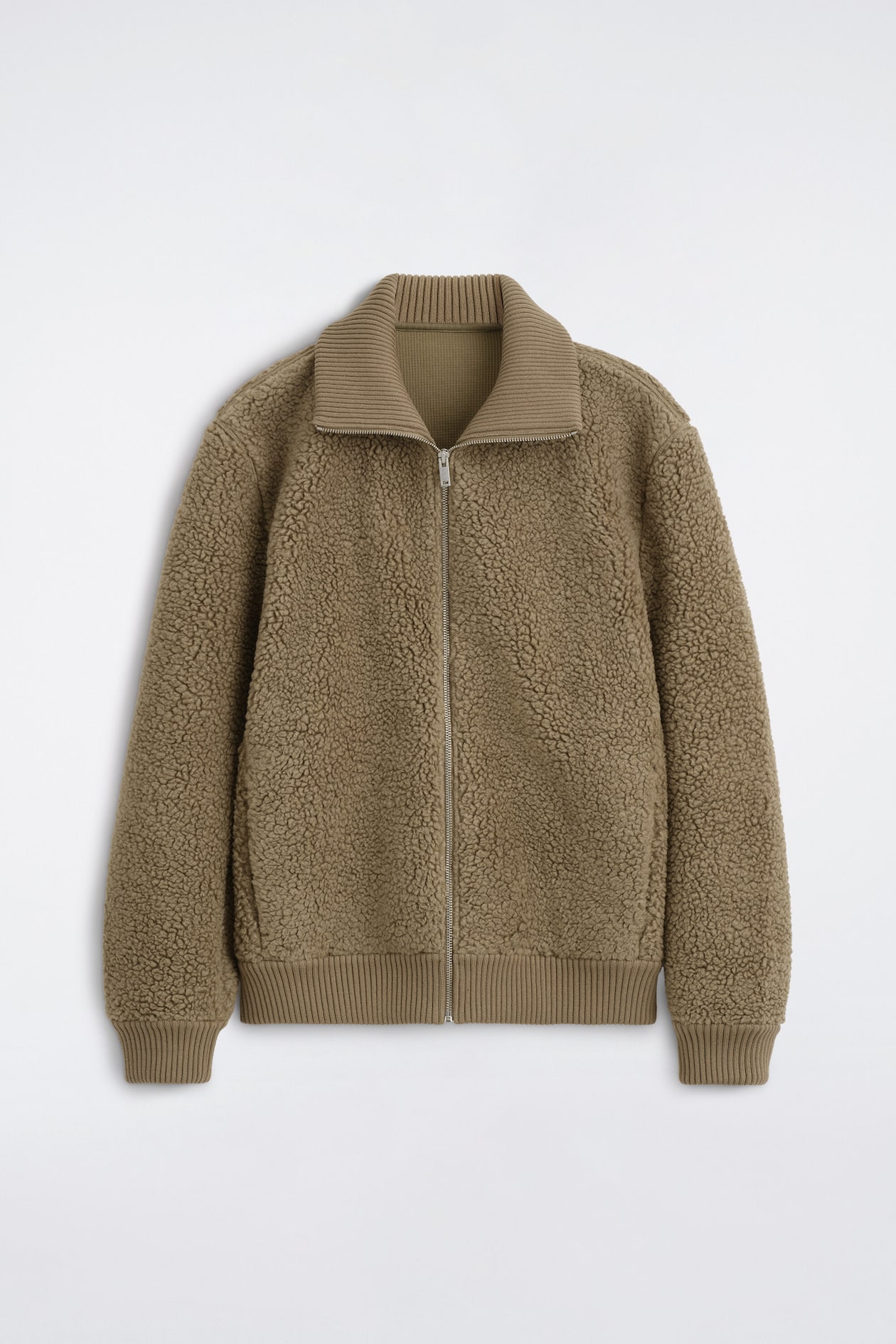 A brown teddy-fleece jacket is shown from the front, featuring a textured exterior, a ribbed knit collar, and matching ribbed cuffs and hem. The jacket features a full-length silver zipper down the centre front.