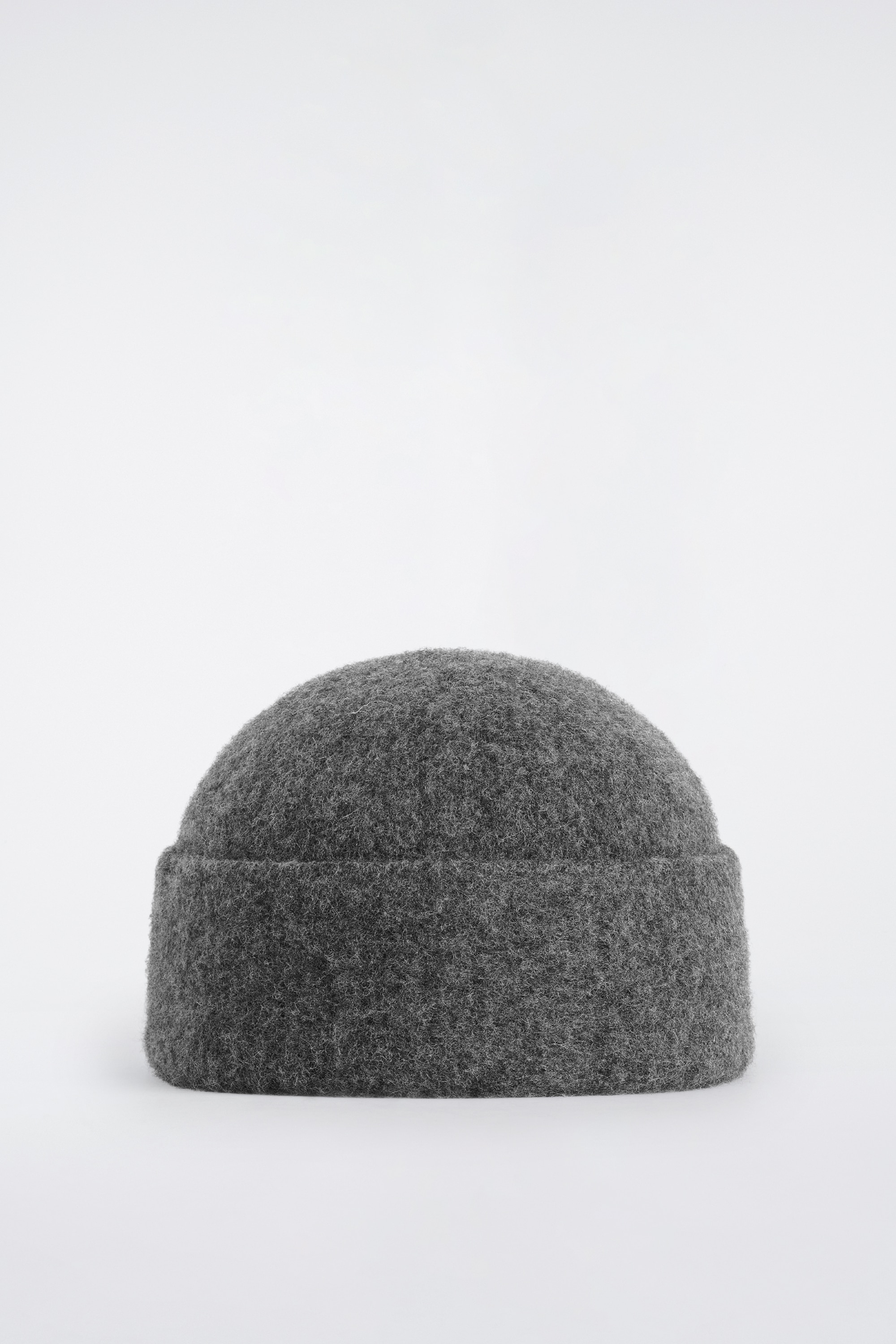 Сива вÑлнена Ñапка Ñип beanie Ñ Ð¿Ð¾Ð´Ð³ÑÐ½Ð°Ñ ÑÑб е ноÑена Ð¾Ñ Ð¼Ð¾Ð´ÐµÐ»Ð°, комбиниÑана Ñ ÑÑмноÑив пÑÐ»Ð¾Ð²ÐµÑ Ñ ÐºÑÑгло деколÑе и каÑÑв вÑлнен палÑо Ñ ÑиÑоки ÑевеÑи.