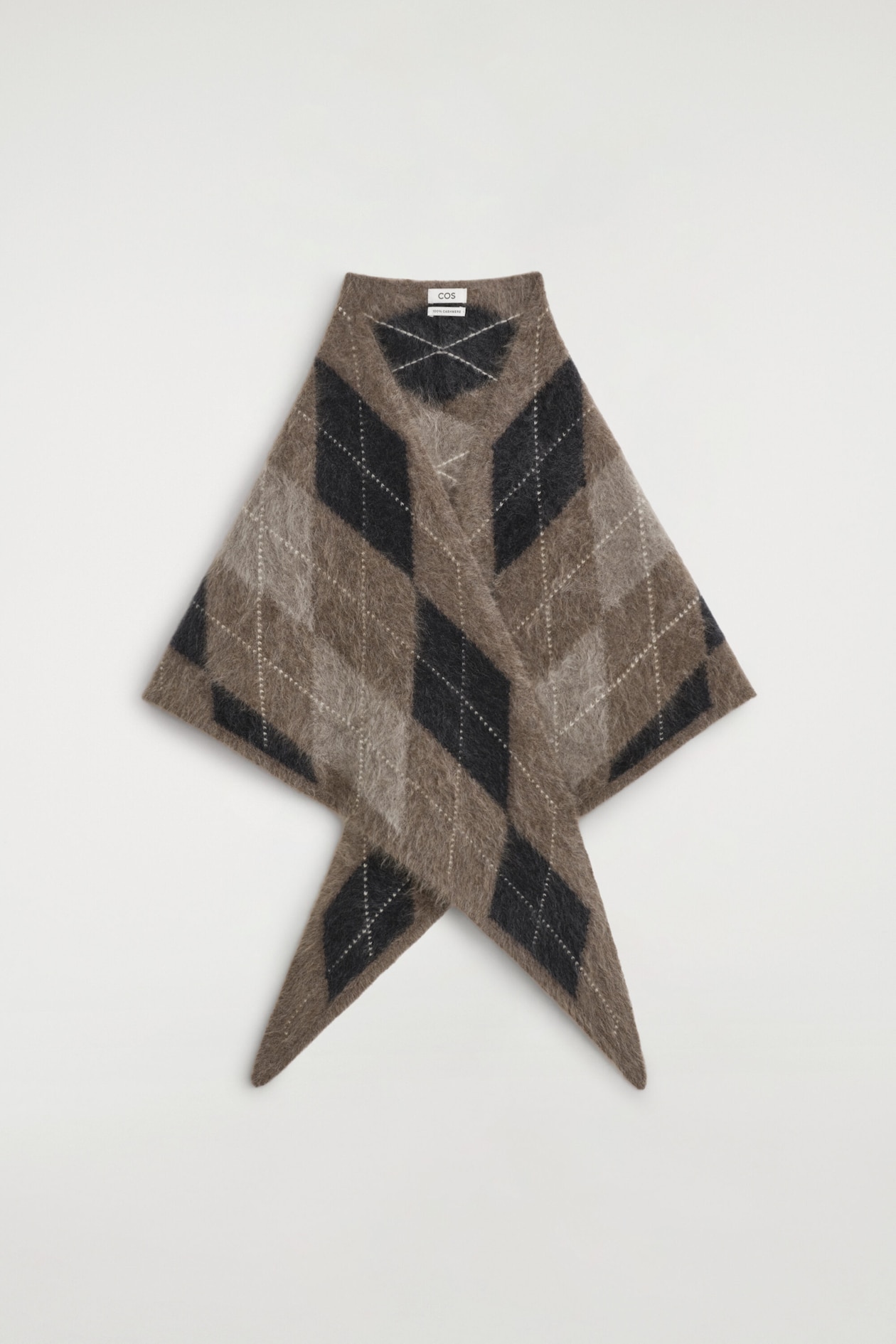 The argyle brushed-cashmere triangle scarf is facing front, displaying a fuzzy, brushed texture with a bold argyle pattern in shades of brown, black, and beige. It features a structured triangular wrap design with two pointed ends crossing over at the bottom.