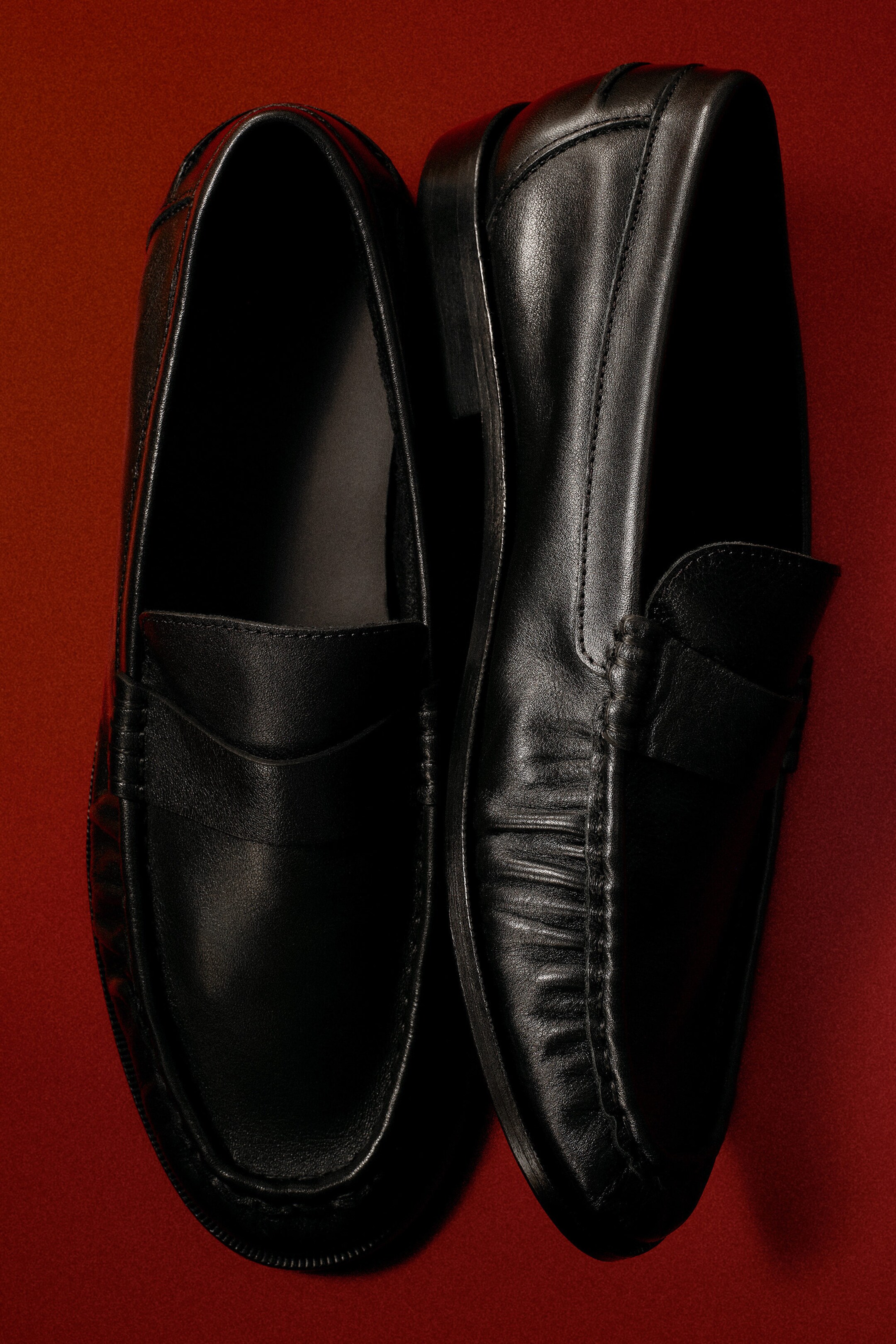 Une paire de mocassins penny noirs en cuir est présentée vue de dessus, mettant en valeur leur design à enfiler. Les mocassins présentent une bride penny classique sur le cou-de-pied, un cuir délicatement froncé le long des coutures latérales et un petit talon bloc. Une paire de mocassins penny noirs en cuir est présentée vue de dessus, mettant en valeur leur design à enfiler. Les mocassins présentent une bride penny classique sur le cou-de-pied, un cuir délicatement froncé le long des coutures latérales et un petit talon bloc.