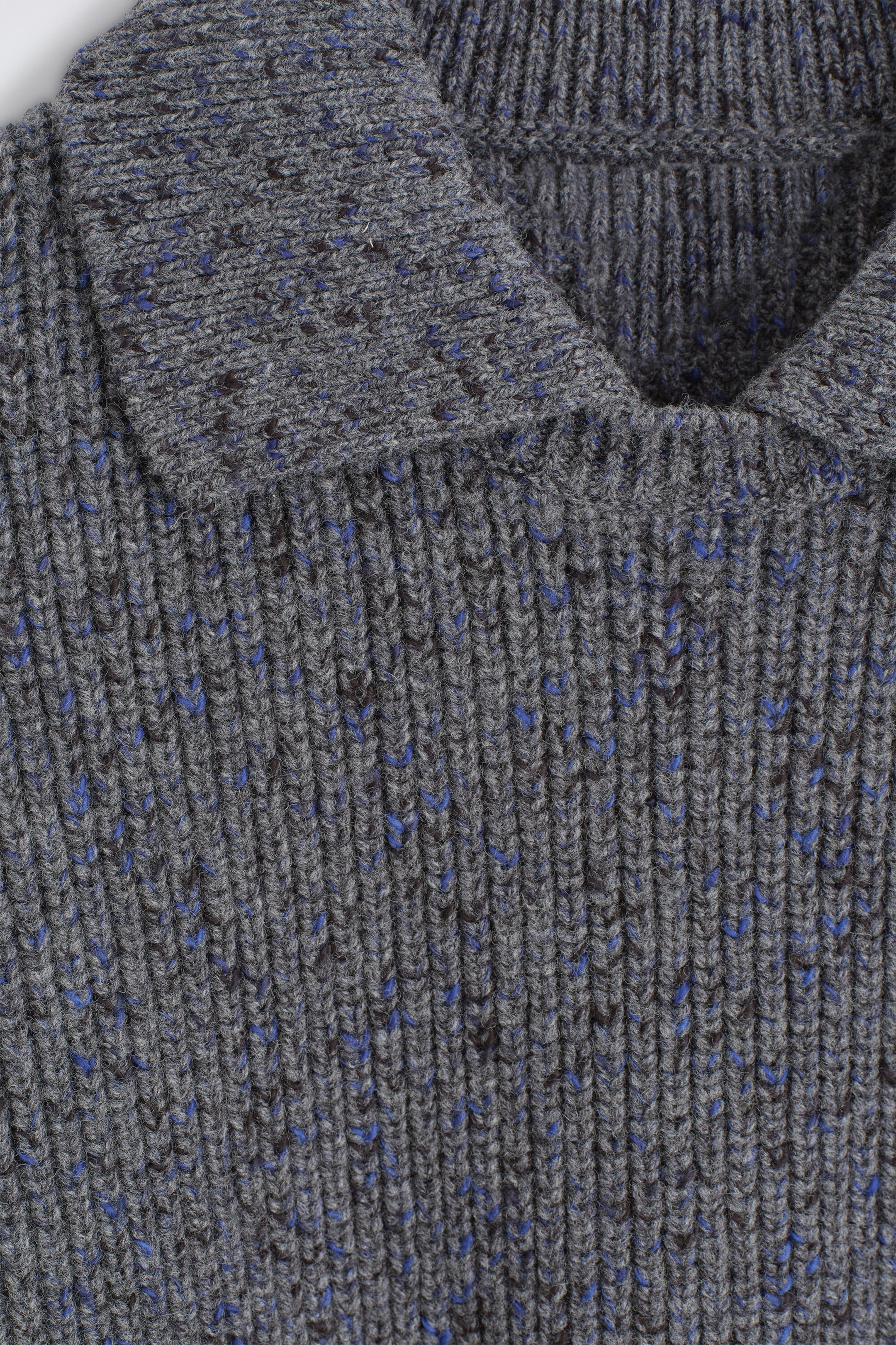 A grey ribbed-knit sweater is showing its front neckline, featuring a flat-knit collar with an open collar design. The textured fabric displays a vertical rib pattern accented with bright blue and dark brown flecks. A grey ribbed-knit sweater is showing its front neckline, featuring a flat-knit collar with an open collar design. The textured fabric displays a vertical rib pattern accented with bright blue and dark brown flecks.