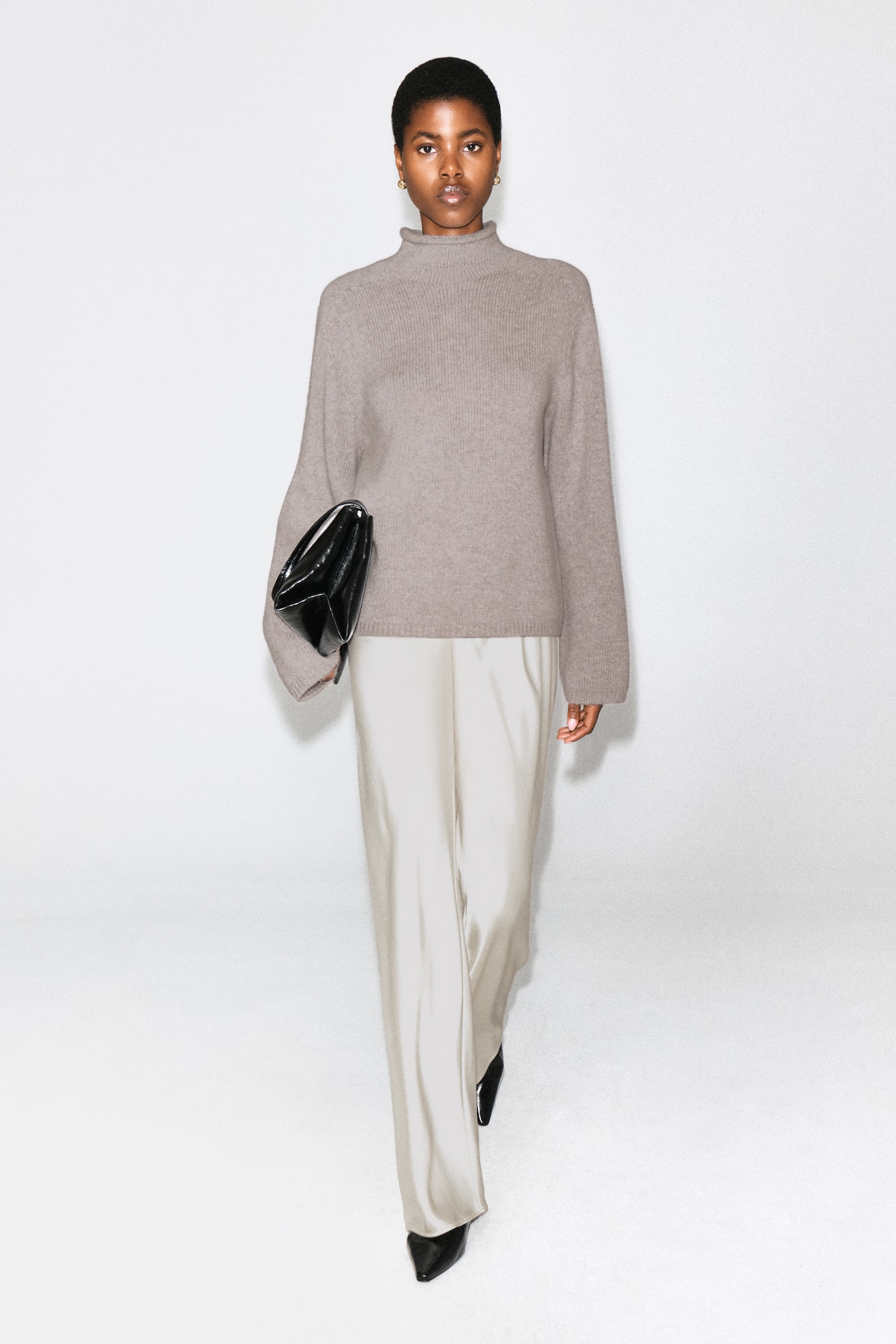 Un par de pantalones de pierna ancha en color beige claro se presenta desde el frente, con una cinturilla elástica y un acabado de brillo suave. - 1