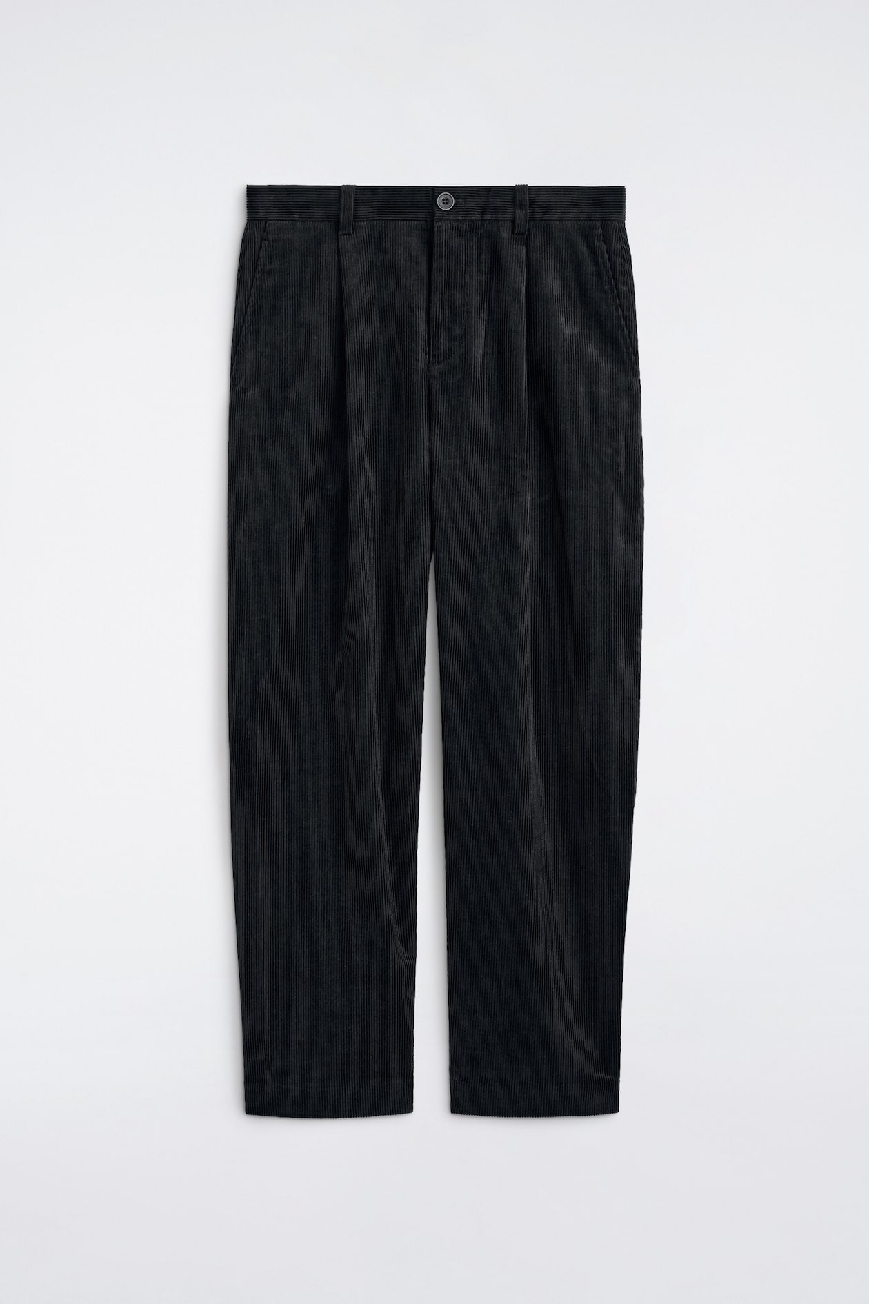 The Pleated Relaxed-Fit Tapered Corduroy Pants are shown from the front, displaying a textured black corduroy fabric with vertical ribbing. The pants feature a relaxed-fit, tapered silhouette with front pleats, belt loops, a button closure, and side slip pockets.