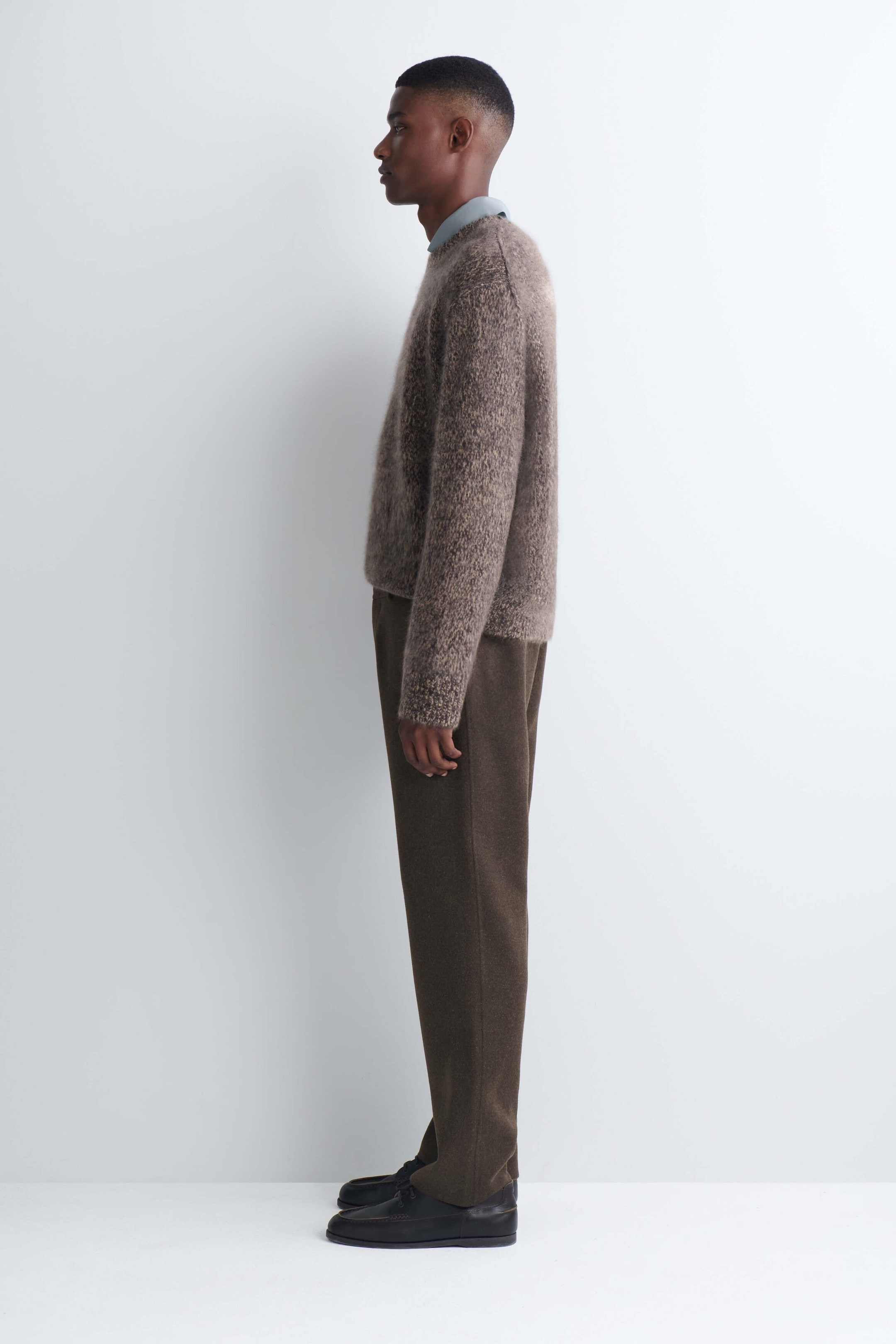 The model is shown in side profile wearing straight-leg pants in a dark brown double-faced wool blend. The clean-cut pants are styled with a textured, fuzzy brown crewneck sweater and dark leather shoes. The model is shown in side profile wearing straight-leg pants in a dark brown double-faced wool blend. The clean-cut pants are styled with a textured, fuzzy brown crewneck sweater and dark leather shoes.