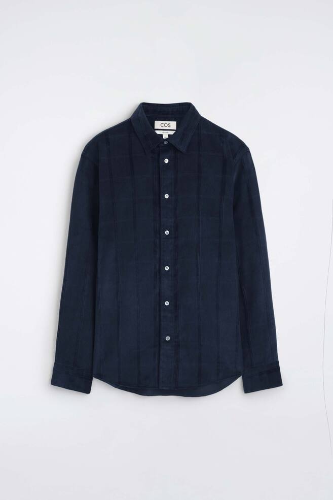 Het casual corduroy overhemd is van voren te zien en toont een donker marineblauwe corduroystof met een subtiele ruitstructuur. Het heeft een puntkraag, een centrale knoopsluiting met contrasterende witte knopen en lange mouwen met manchetten met knoopsluiting. - 1