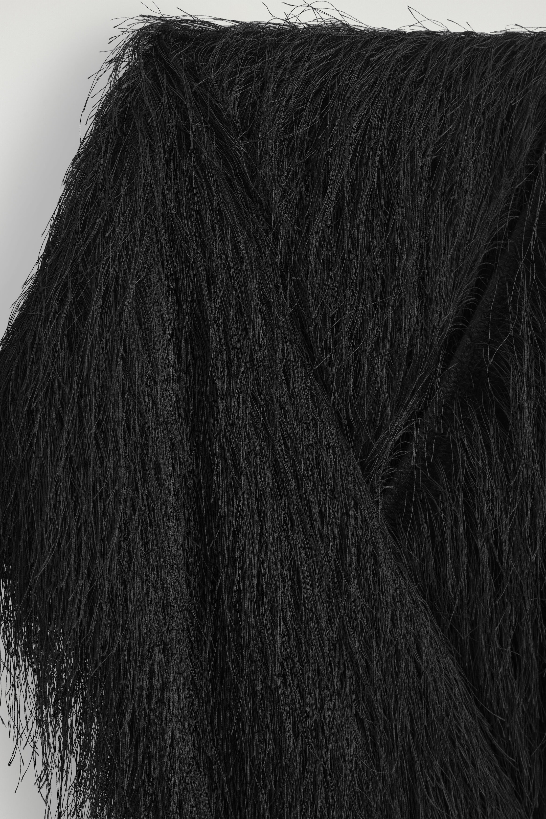 A black scarf is displayed with a highly textured surface entirely covered in dense, wispy fringe. The fine-threaded layers drape downward, creating a voluminous, layered appearance.