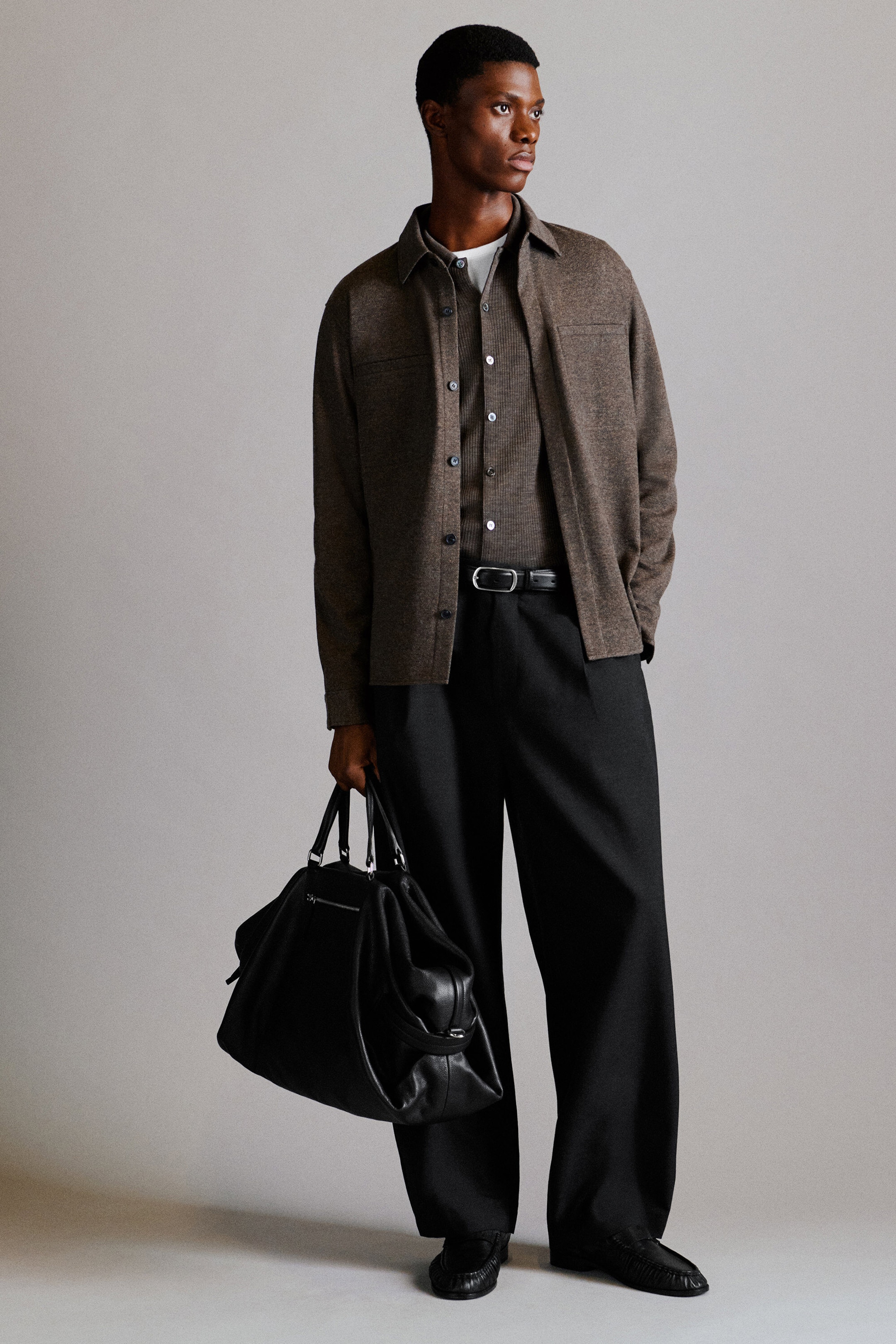 The belt-detail wool relaxed-fit barrel-leg trousers feature a wide, slightly tapered barrel-leg silhouette in dark charcoal. Seen from the front, the trousers drape loosely with front pleats and showcase a black leather belt with a silver-tone buckle at the waist. The belt-detail wool relaxed-fit barrel-leg trousers feature a wide, slightly tapered barrel-leg silhouette in dark charcoal. Seen from the front, the trousers drape loosely with front pleats and showcase a black leather belt with a silver-tone buckle at the waist.