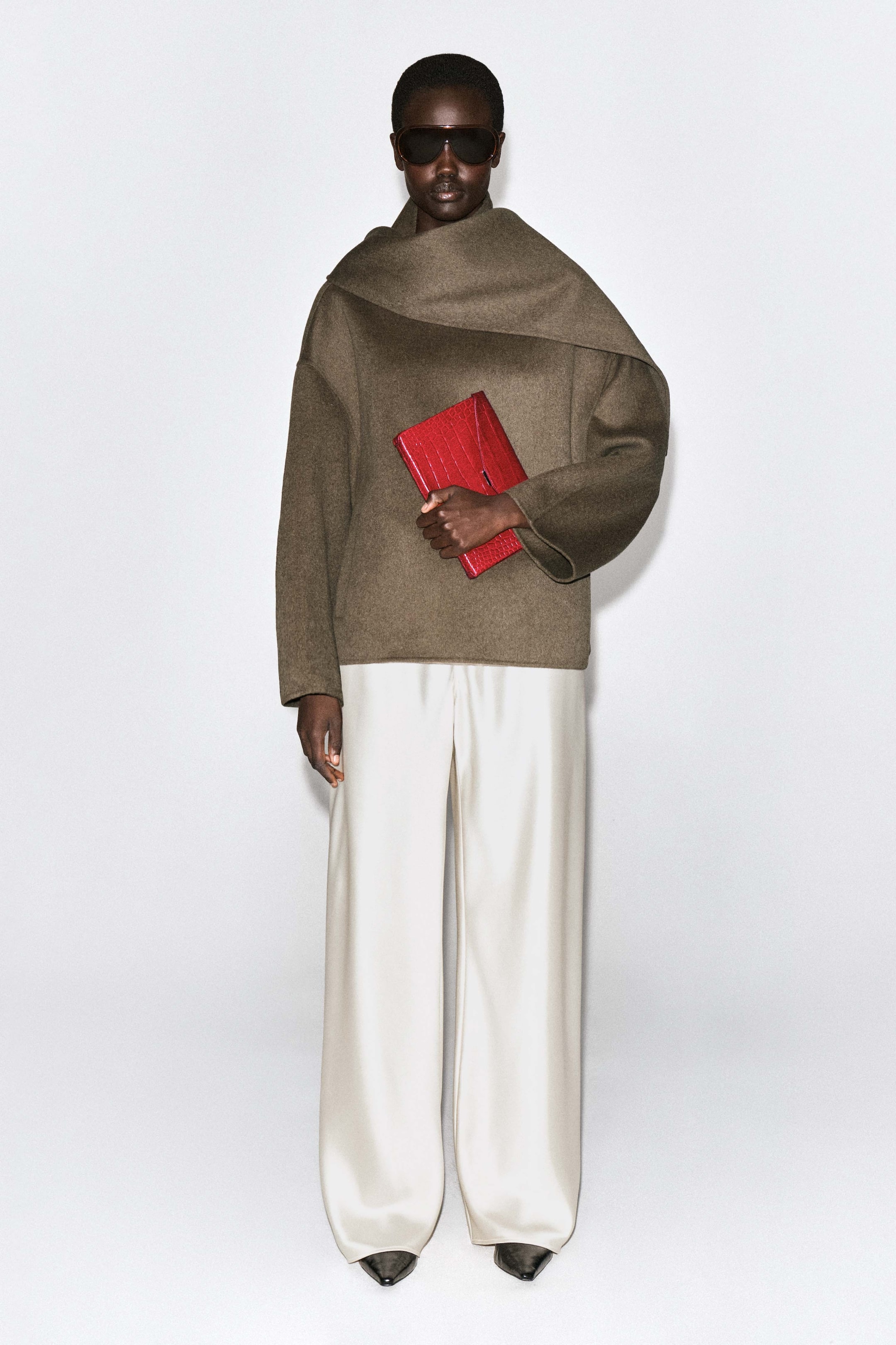 Ver imagen más grande: La cartera Envelope Clasp en piel roja con efecto cocodrilo se sostiene en una vista frontal, mostrando su diseño rectangular estructurado y su acabado texturizado. La cartera presenta una solapa triangular tipo sobre con un discreto cierre de broche.