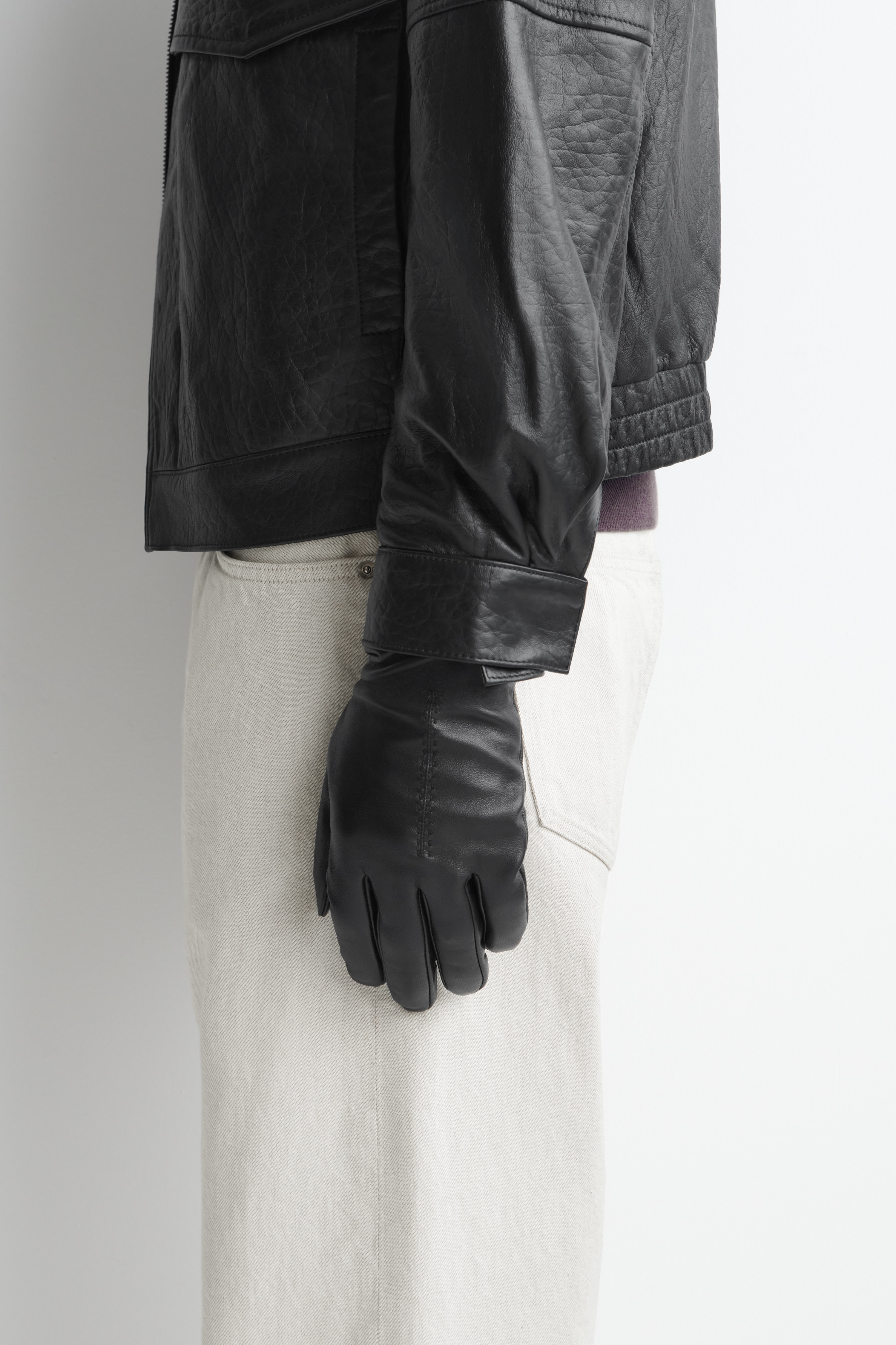 Mit Kaschmir gefÃ¼tterte Lederhandschuhe liegen flach, wobei ein Handschuh die RÃ¼ckseite der Hand und der andere die HandflÃ¤chenseite zeigt. Der linke Handschuh zeigt eine mittig verlaufende vertikale Ziernaht, wÃ¤hrend der rechte ein elastisches HandgelenkbÃ¼ndchen mit Riemenverschluss und Druckknopf aufweist.