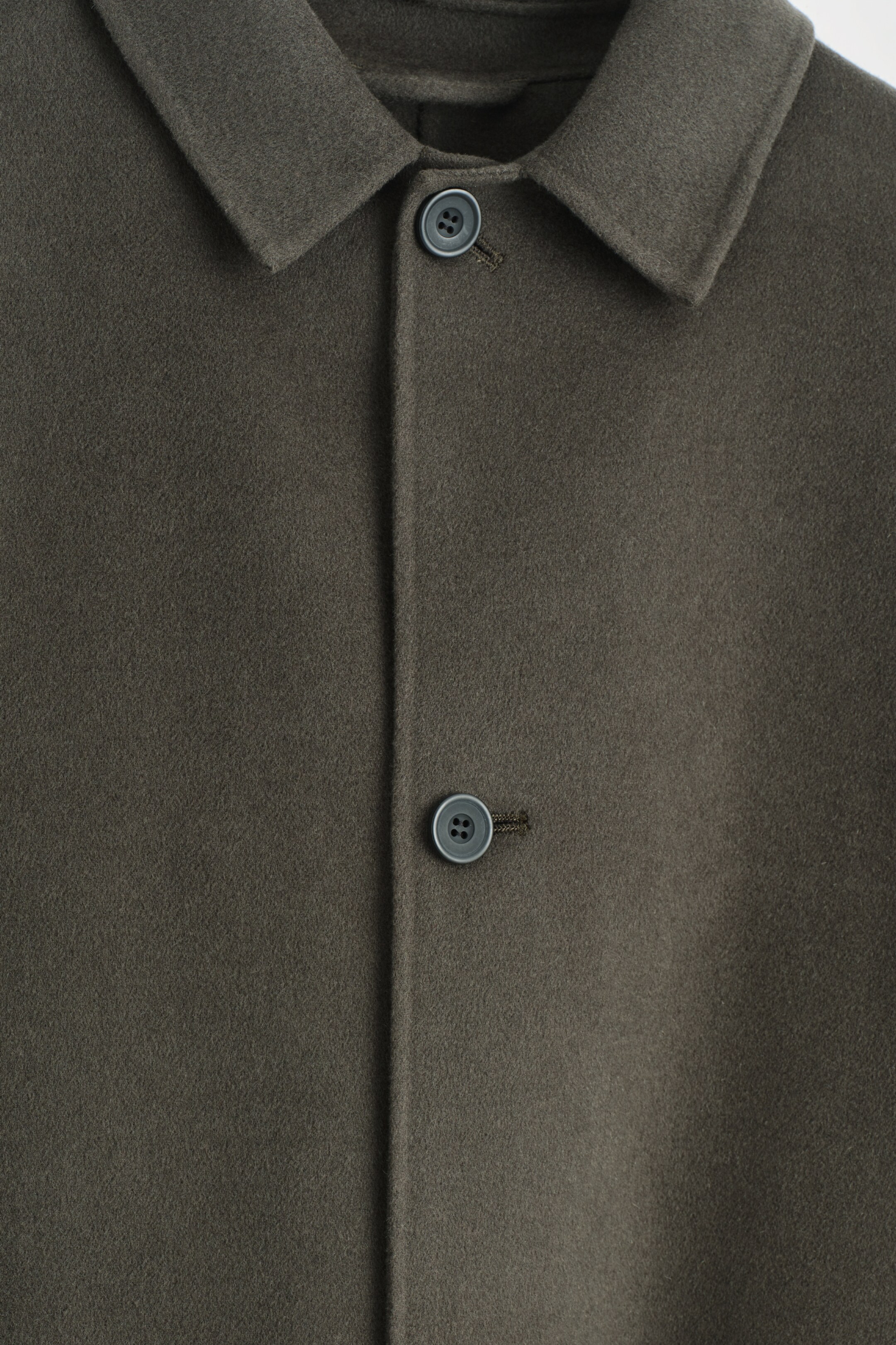 Ingrandisci l'immagine: La PARTE ANTERIORE di un cappotto color espresso è visibile, realizzato in un tessuto fine e peloso e caratterizzato da un colletto a punta. Due bottoni grigio scuro chiudono la lista frontale.