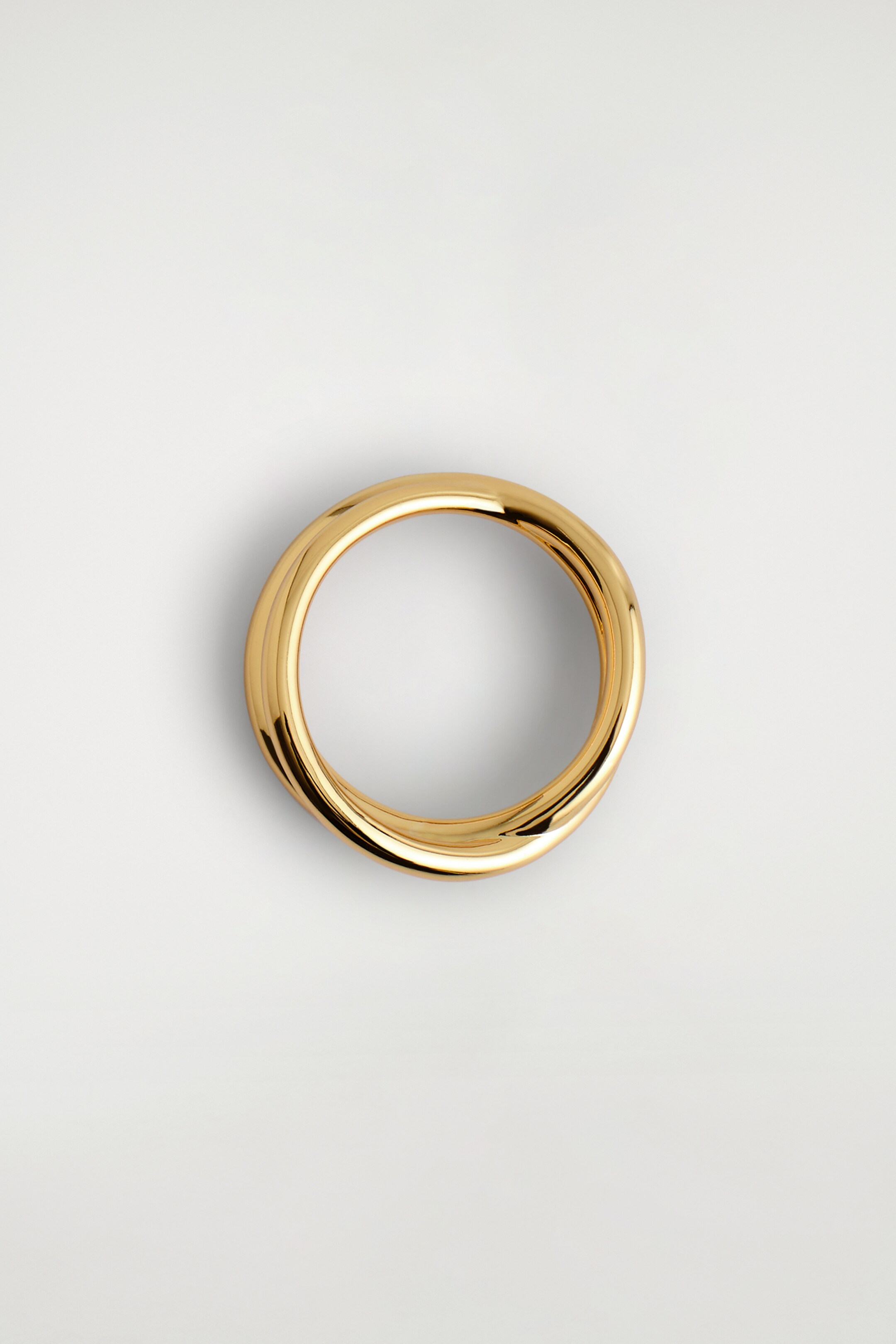 Visualizza immagine più grande: Un anello color oro è presentato da una vista dall'alto, caratterizzato da un design a doppio avvolgimento ondulato con una superficie liscia e lucida.