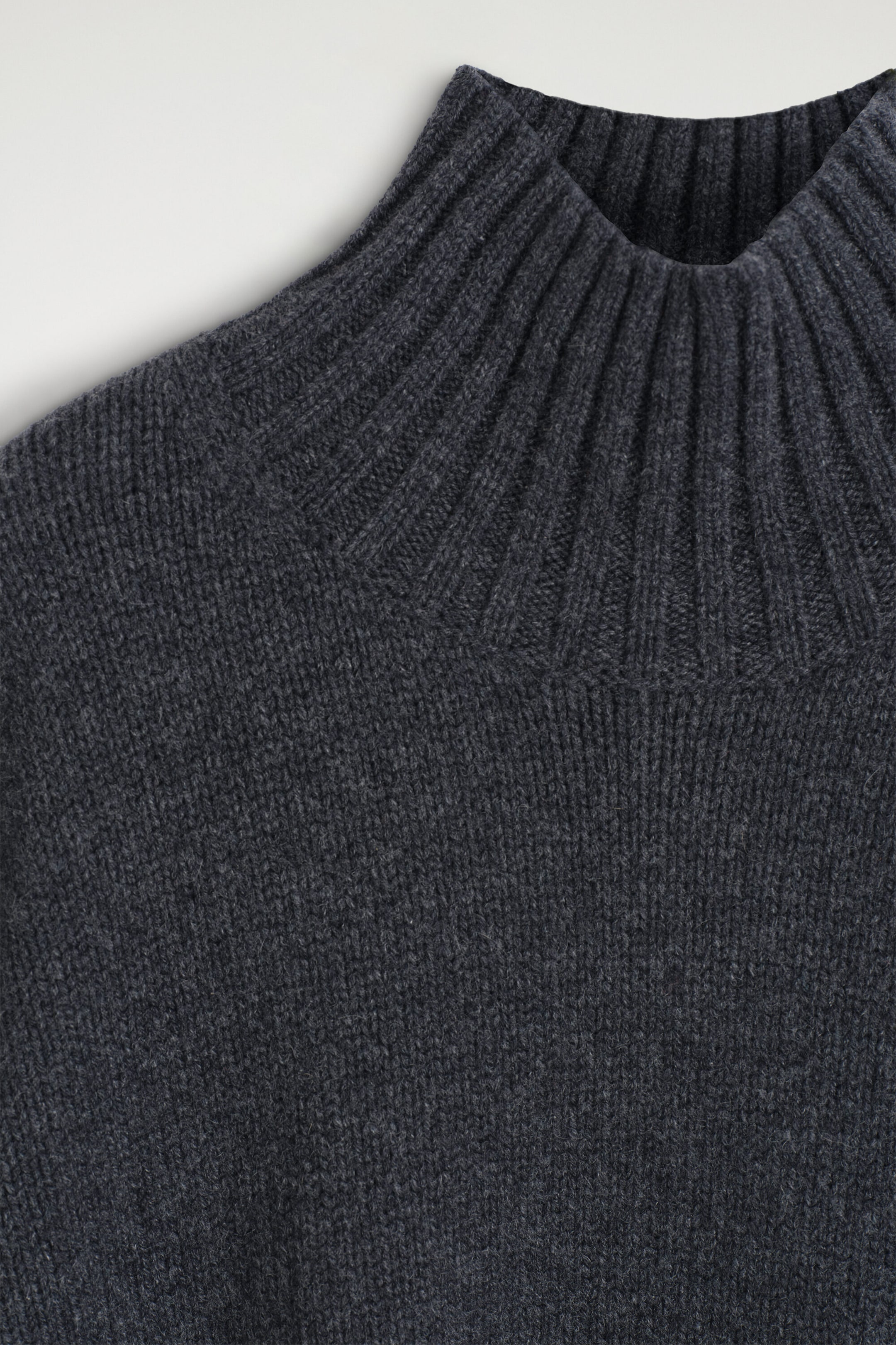 The chunky cashmere funnel-neck jumper is shown in a close-up focusing on the front neckline, highlighting its dark grey ribbed funnel neck and textured knitted body. The chunky cashmere funnel-neck jumper is shown in a close-up focusing on the front neckline, highlighting its dark grey ribbed funnel neck and textured knitted body.