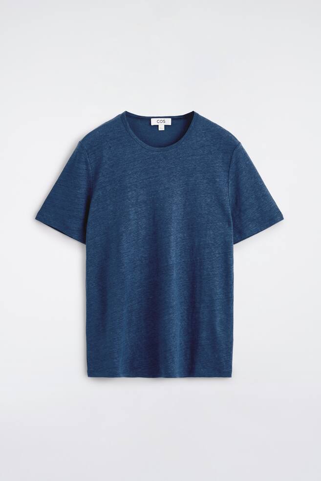Una t-shirt presentata di fronte, realizzata in tessuto di lino blu scuro con una trama visibile. È caratterizzata da maniche corte e un collo a girocollo arrotondato con una fascia stretta, mostrando una vestibilità rilassata e dritta. - 1