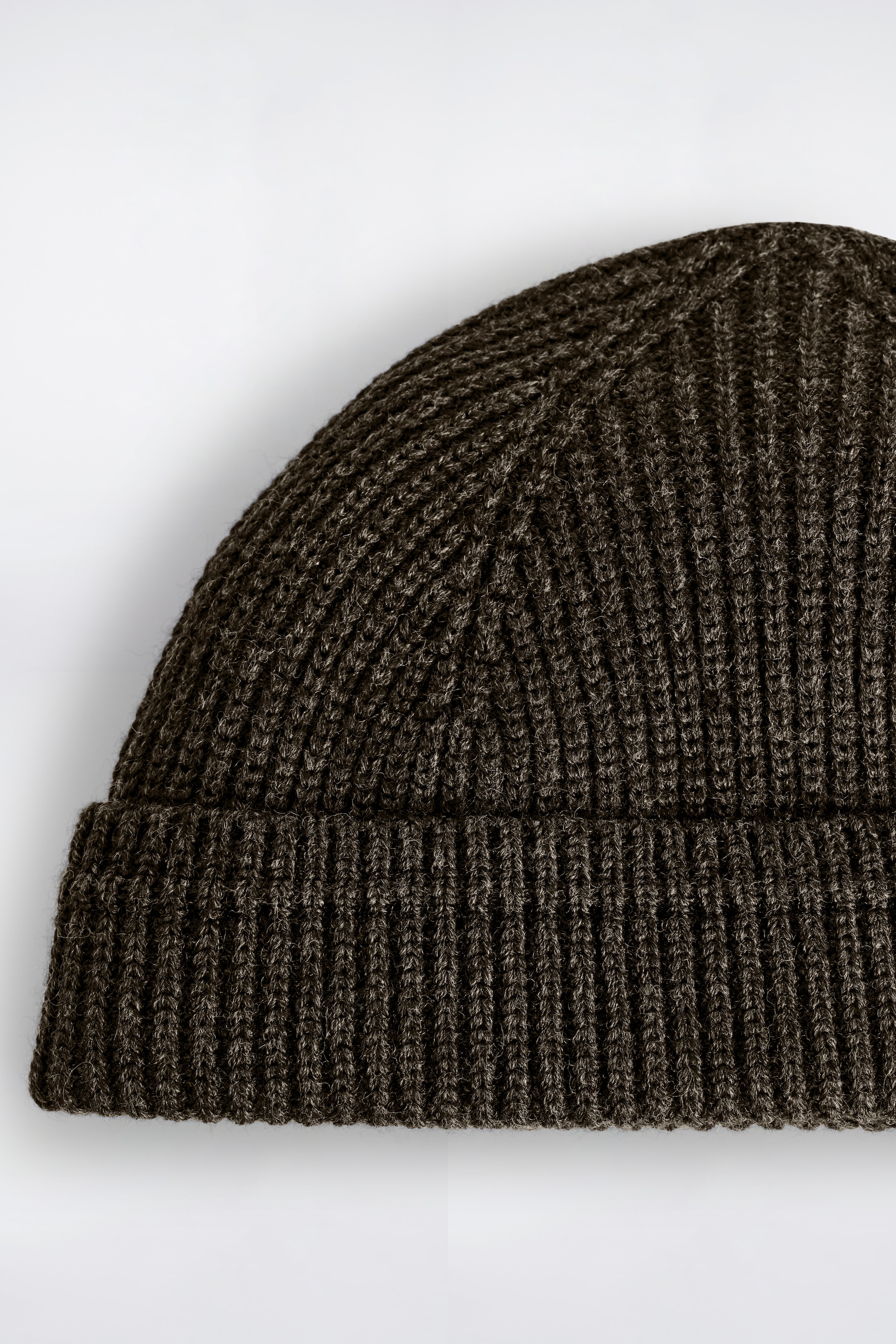 Agrandir l'image: Un bonnet vert olive foncé présente une texture en maille côtelée épaisse et un bord court replié.