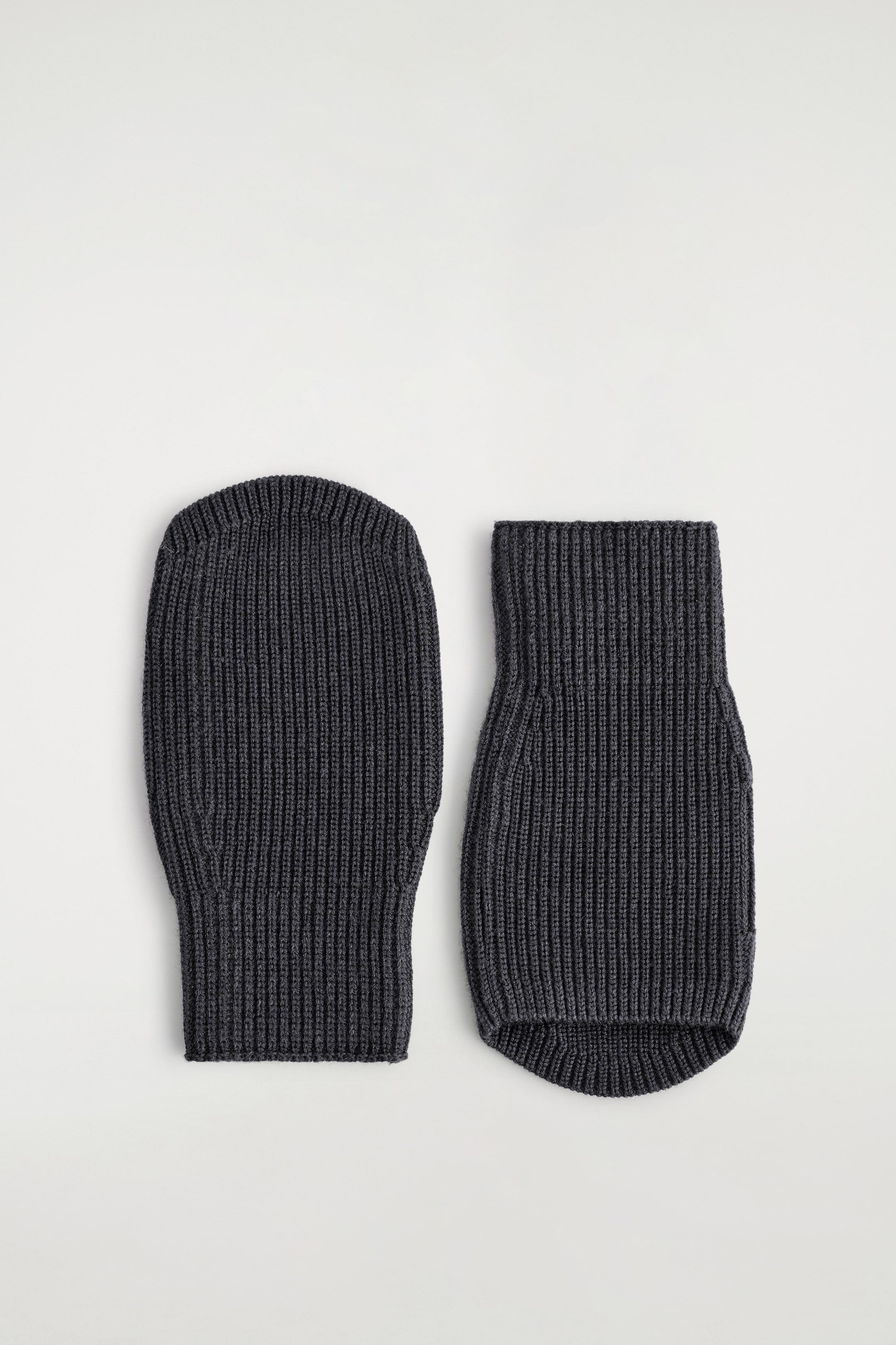 Agrandir l'image: Un bonnet en tricot côtelé gris foncé avec une couronne arrondie est posé à plat à côté d'un tour de cou tubulaire assorti. Le tour de cou présente une forme légèrement évasée et un bord inférieur incurvé.