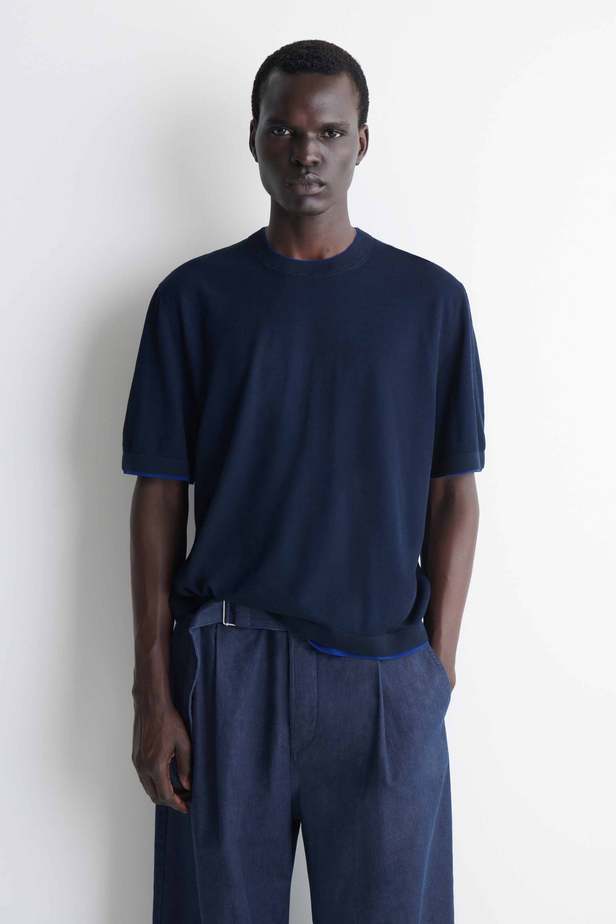 Visualizza l'immagine ingrandita: Un top blu navy a maniche corte con girocollo viene presentato frontalmente, con un bordo blu a contrasto visibile sulle estremità delle maniche e sull’orlo.