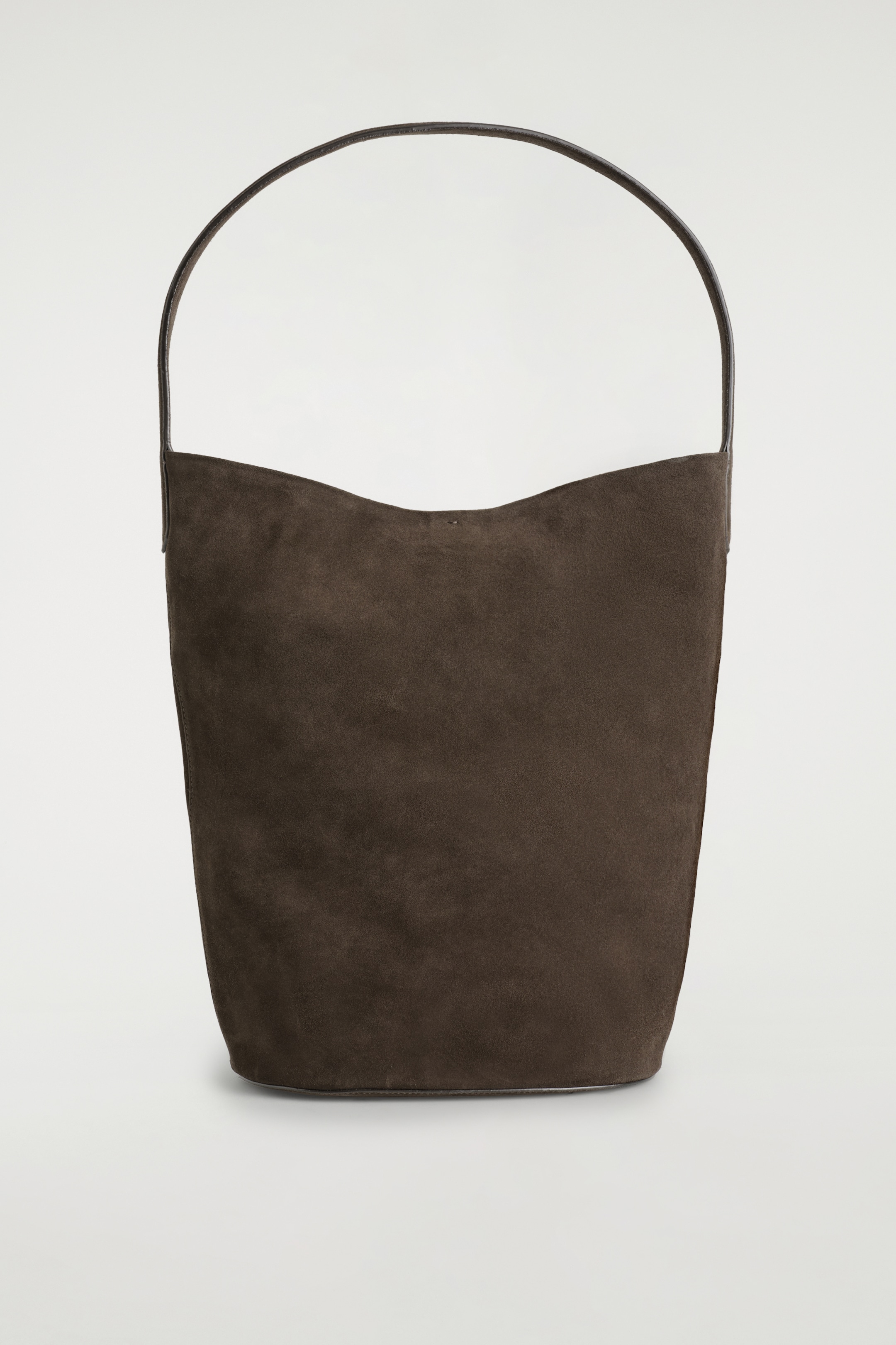 Visualizza immagine più grande: Una tote bag in camoscio marrone scuro mostra la parte anteriore, caratterizzata da una silhouette morbida con un'apertura superiore curva. Un manico unico, sottile e scuro si inarca sopra la borsa.
