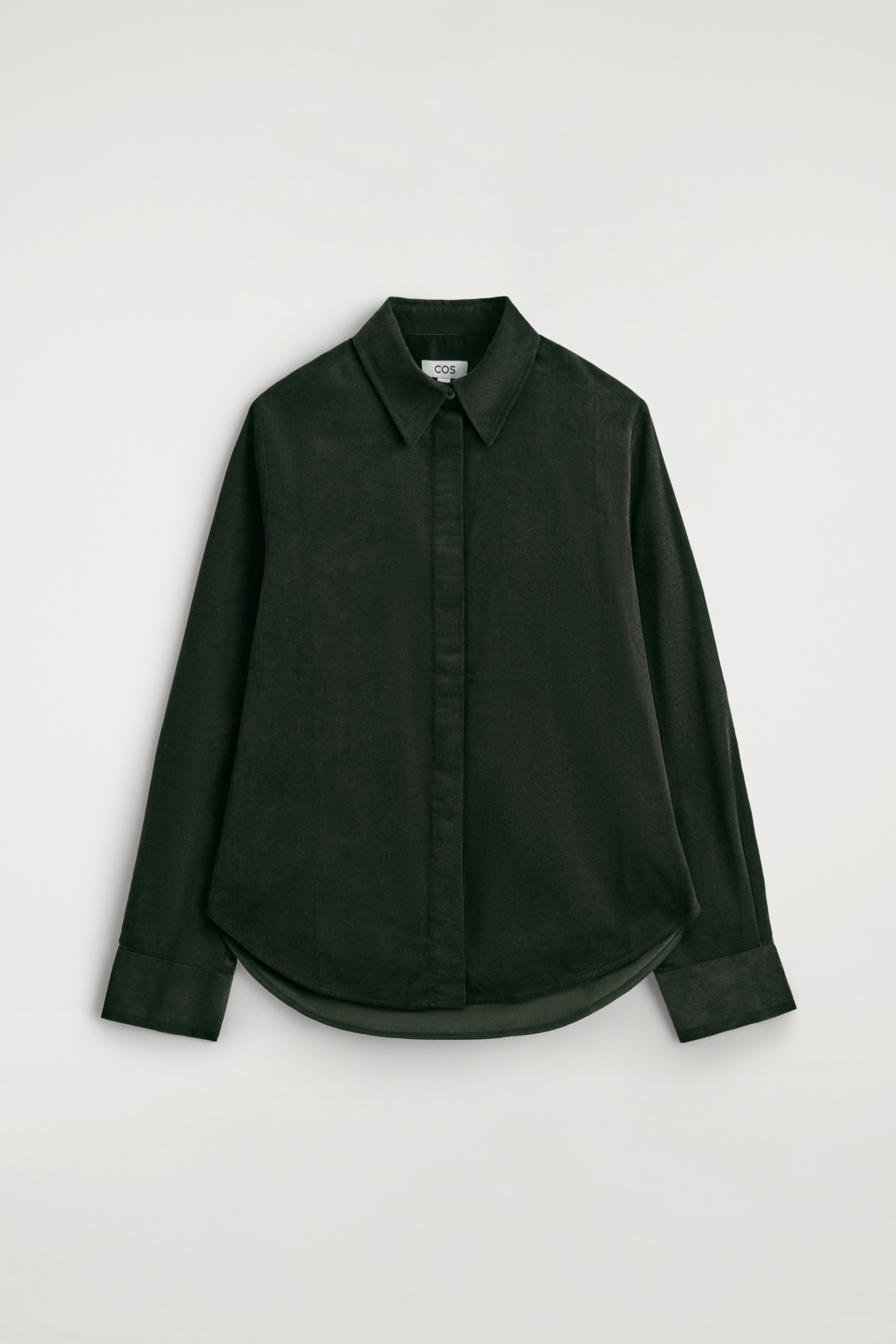 Ver imagem maior: Uma camisa de bombazina de algodão verde escuro está a ser apresentada de frente, exibindo um corte regular, uma gola pontiaguda, uma carcela de botões oculta na frente, mangas compridas com punhos e uma bainha curva.