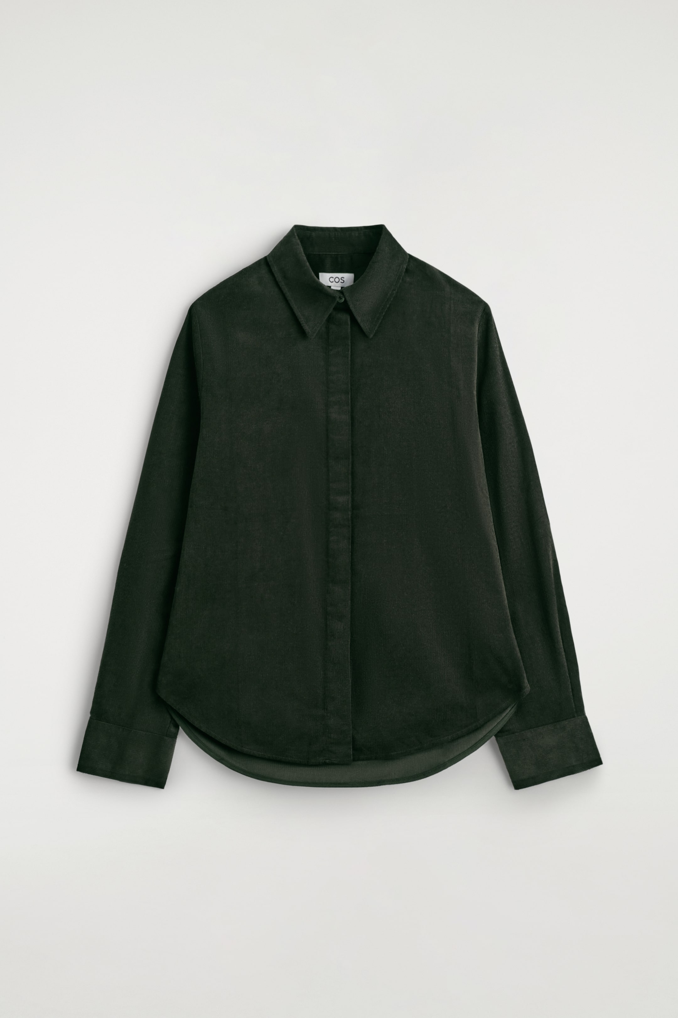 Visualizza immagine più grande: Una camicia in velluto a coste di cotone verde scuro viene presentata dal davanti, mostrando una vestibilità regolare, un colletto a punta, un'abbottonatura nascosta lungo la parte anteriore, maniche lunghe con polsini e un orlo arrotondato.