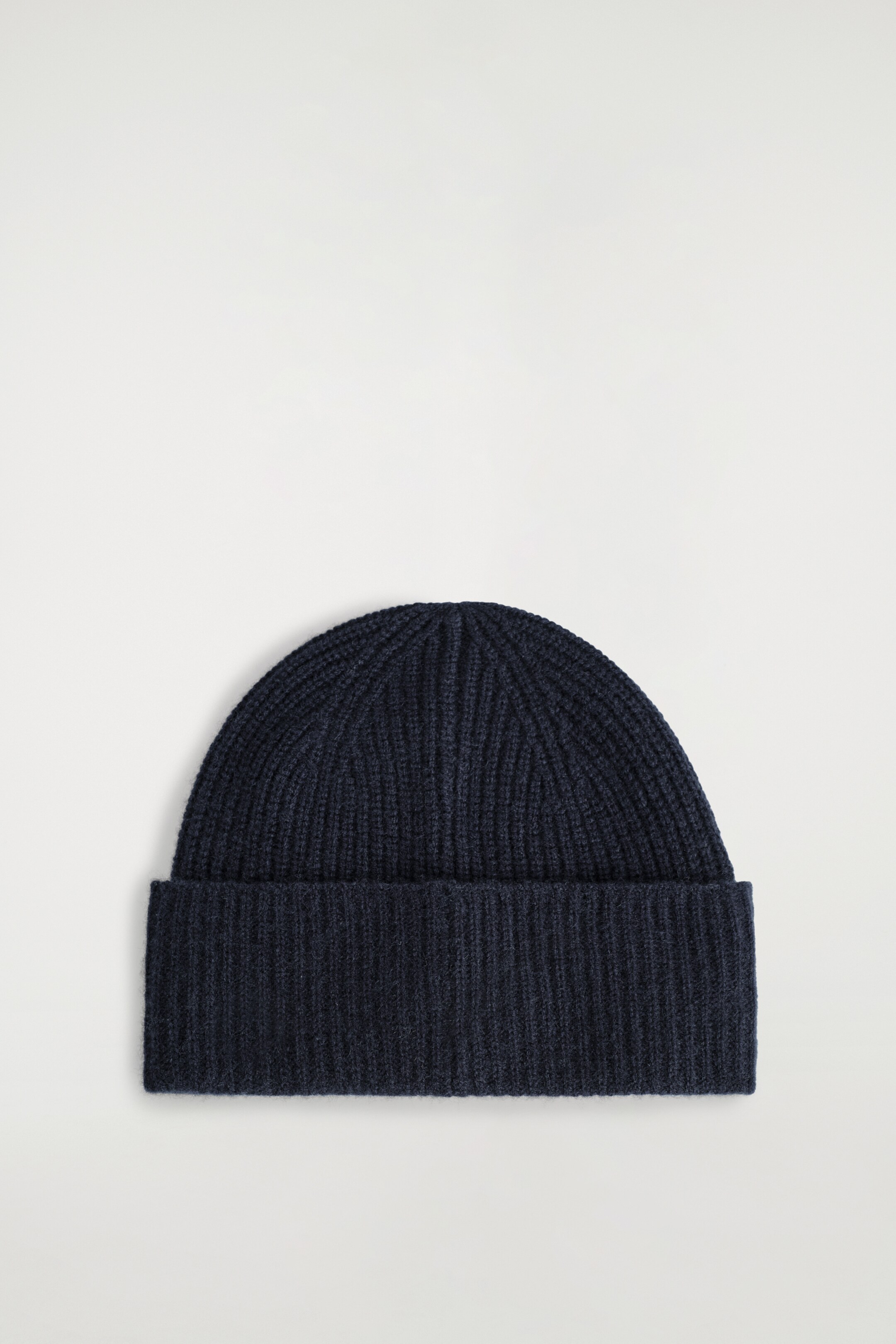View larger image: A dark blue beanie is presenting a vertically ribbed knit pattern. It is featuring a wide, folded brim.