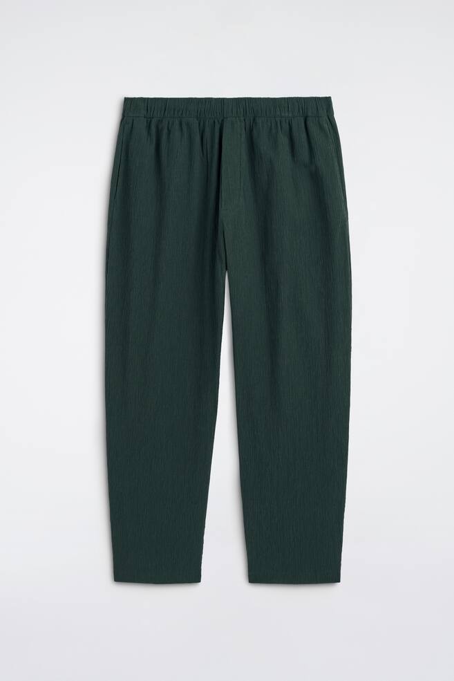 Diese smaragdgrünen Hosen zeigen eine sichtbare, geknitterte Textur auf der Vorderseite. Sie verfügen über einen elastischen Bund, Seitentaschen und einen entspannten Schnitt an den Beinen. - 1