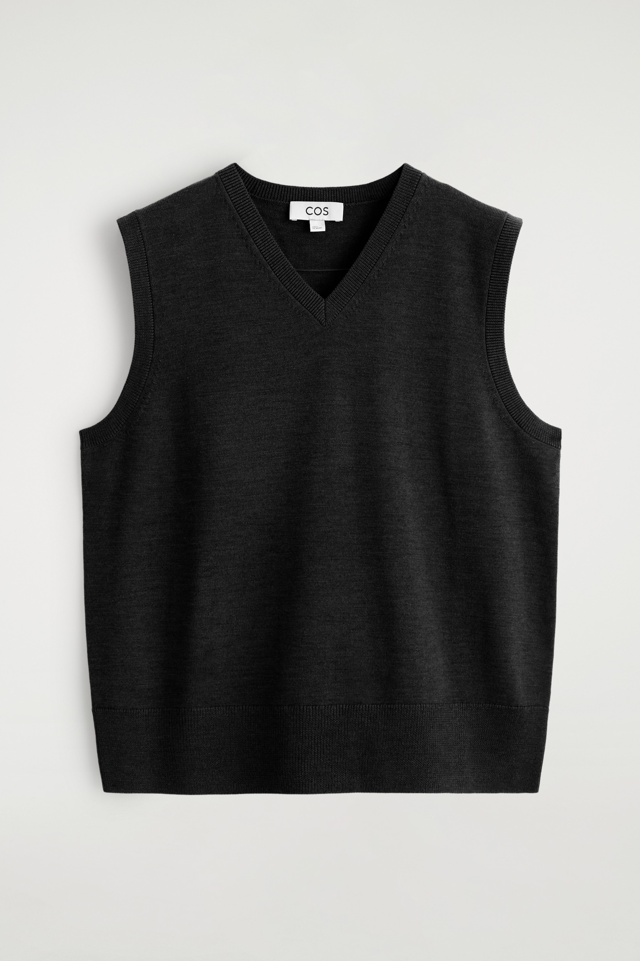 Größeres Bild ansehen: Ein schwarzer ärmelloser Pullover wird von vorne gezeigt, mit einem V-Ausschnitt und gerippten Abschlüssen entlang des Ausschnitts, der Armlöcher und des unteren Saums.